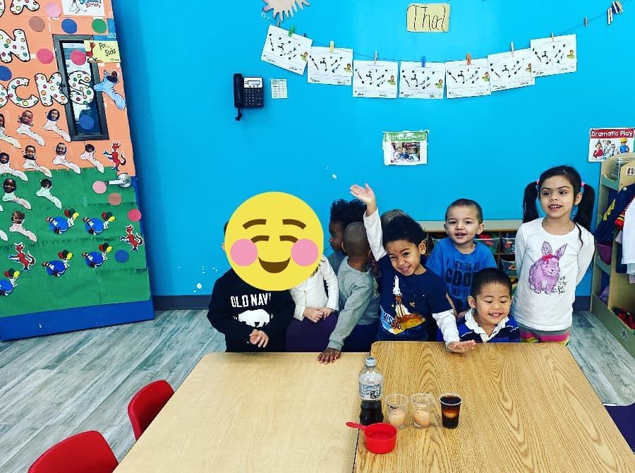 A group of children are sitting around a table with a smiley face on their face