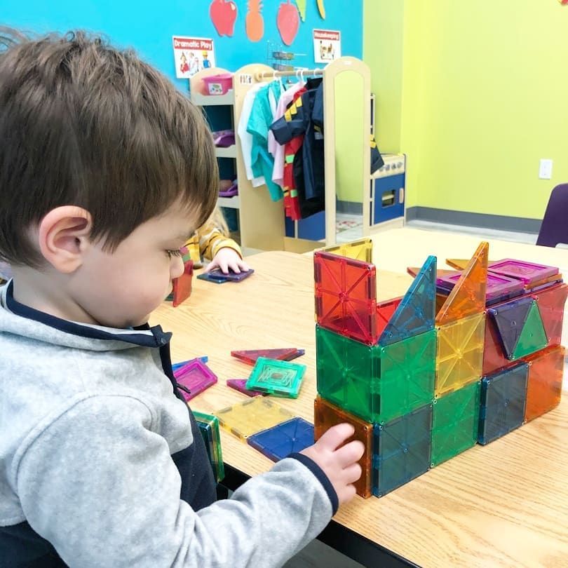 A young boy is playing with magnetic blocks on a table