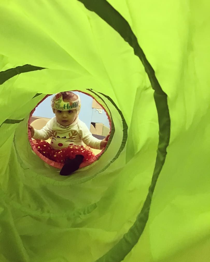 A baby is playing in a green tunnel