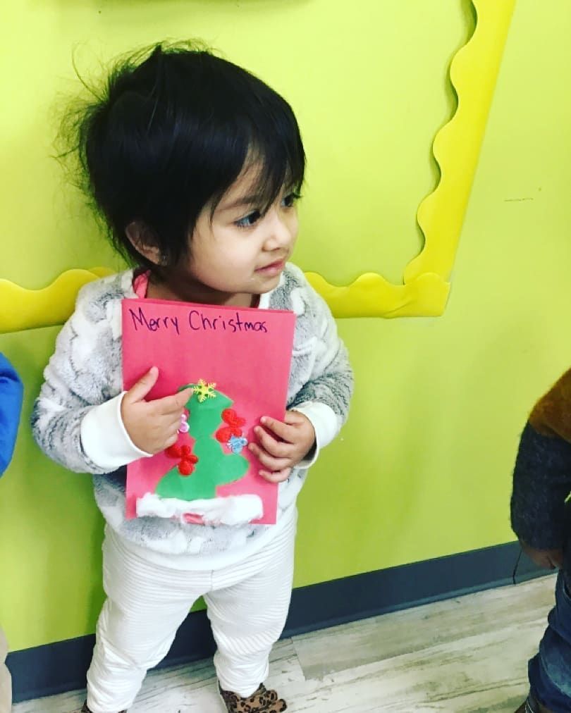 A little boy is holding a card that says merry christmas