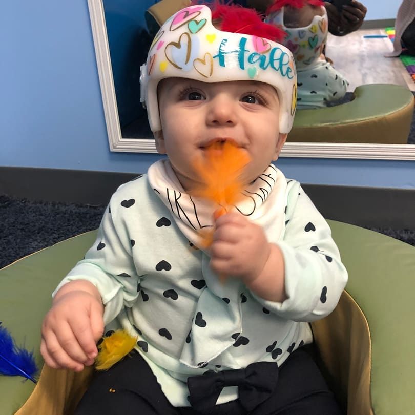 A baby wearing a helmet with the name halle on it