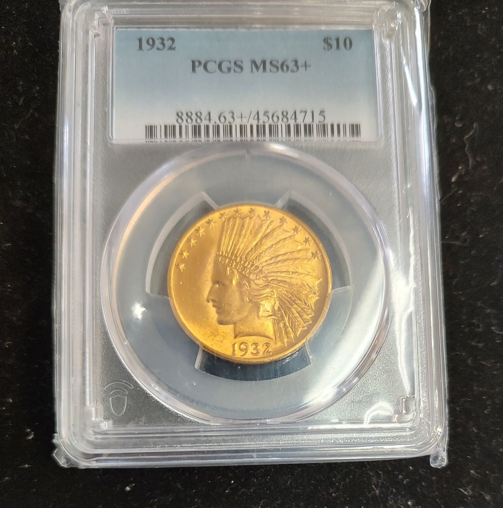 Gold coin in a clear plastic case, graded by PCGS as MS63+.