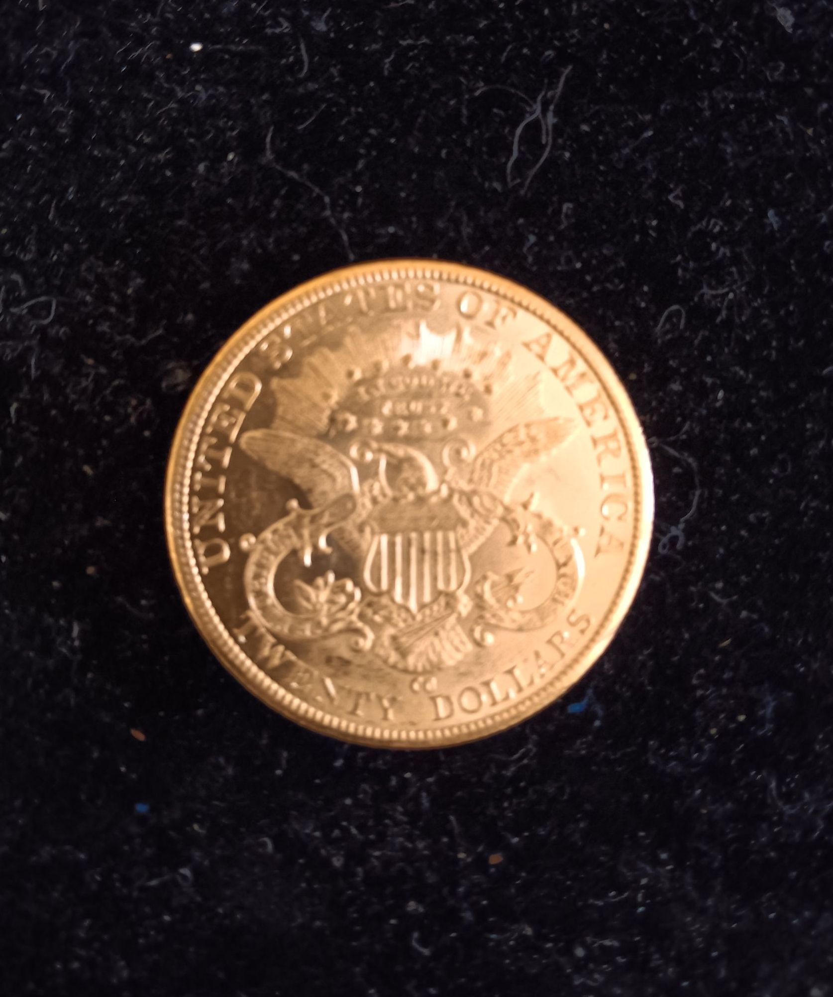 Gold coin with an eagle design, "UNITED STATES OF AMERICA" and "TWENTY DOLLARS" text.