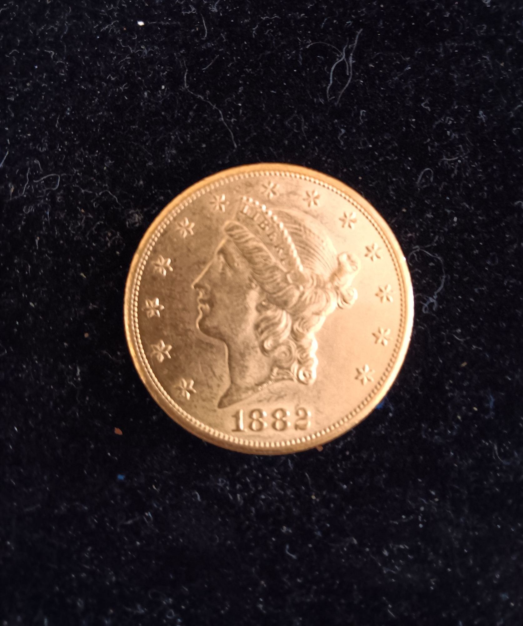 Gold coin with Liberty head, stars, and date "1869" on a black surface.