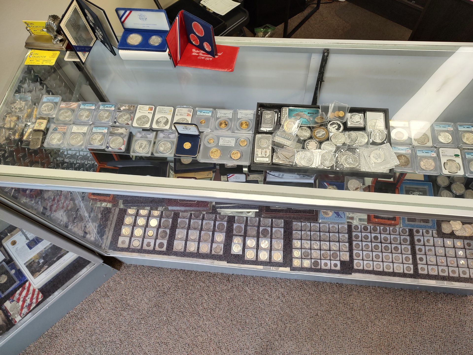 A glass display case filled with coins, graded and ungraded.