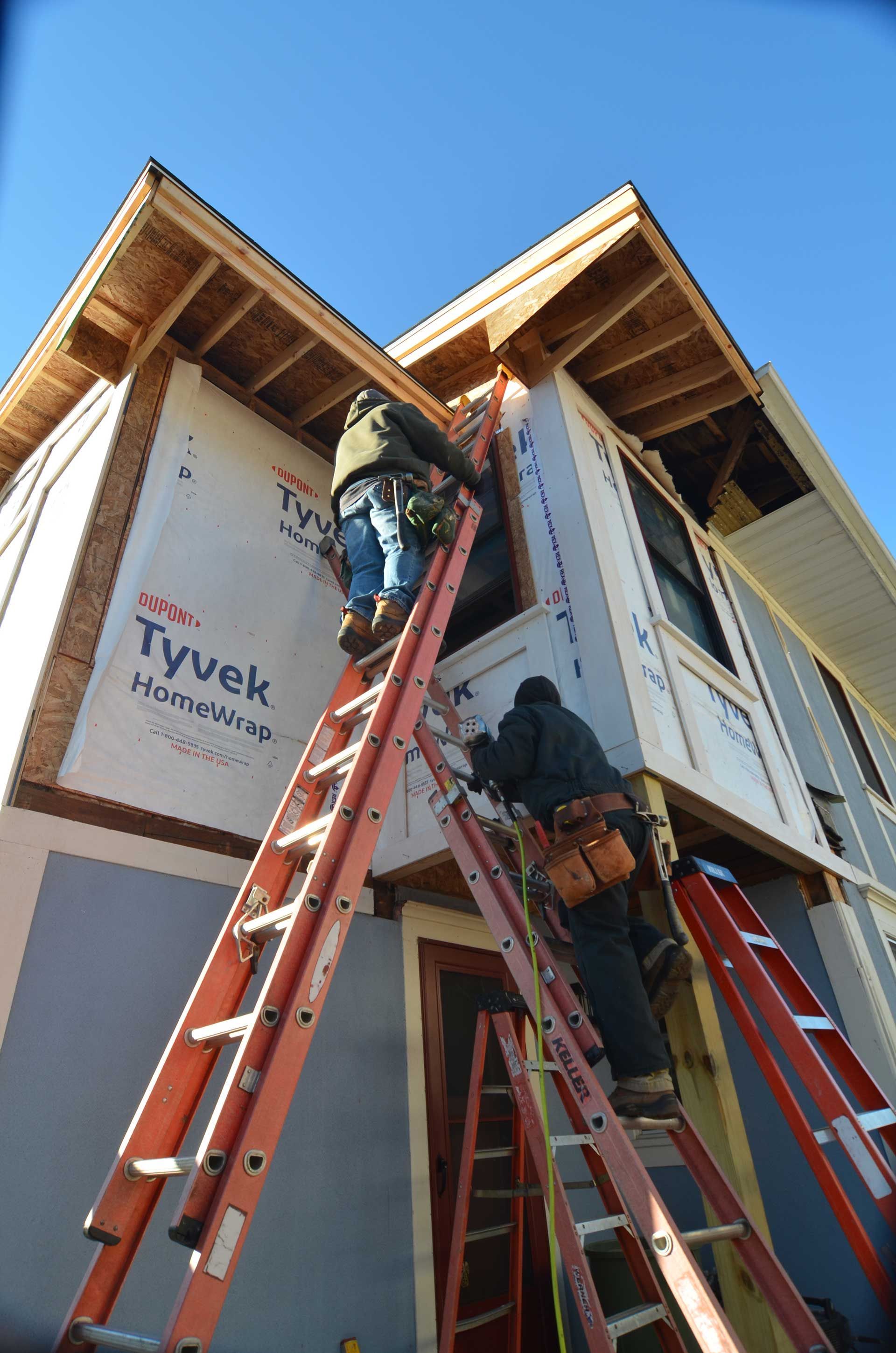 Two workers climbing a ladder