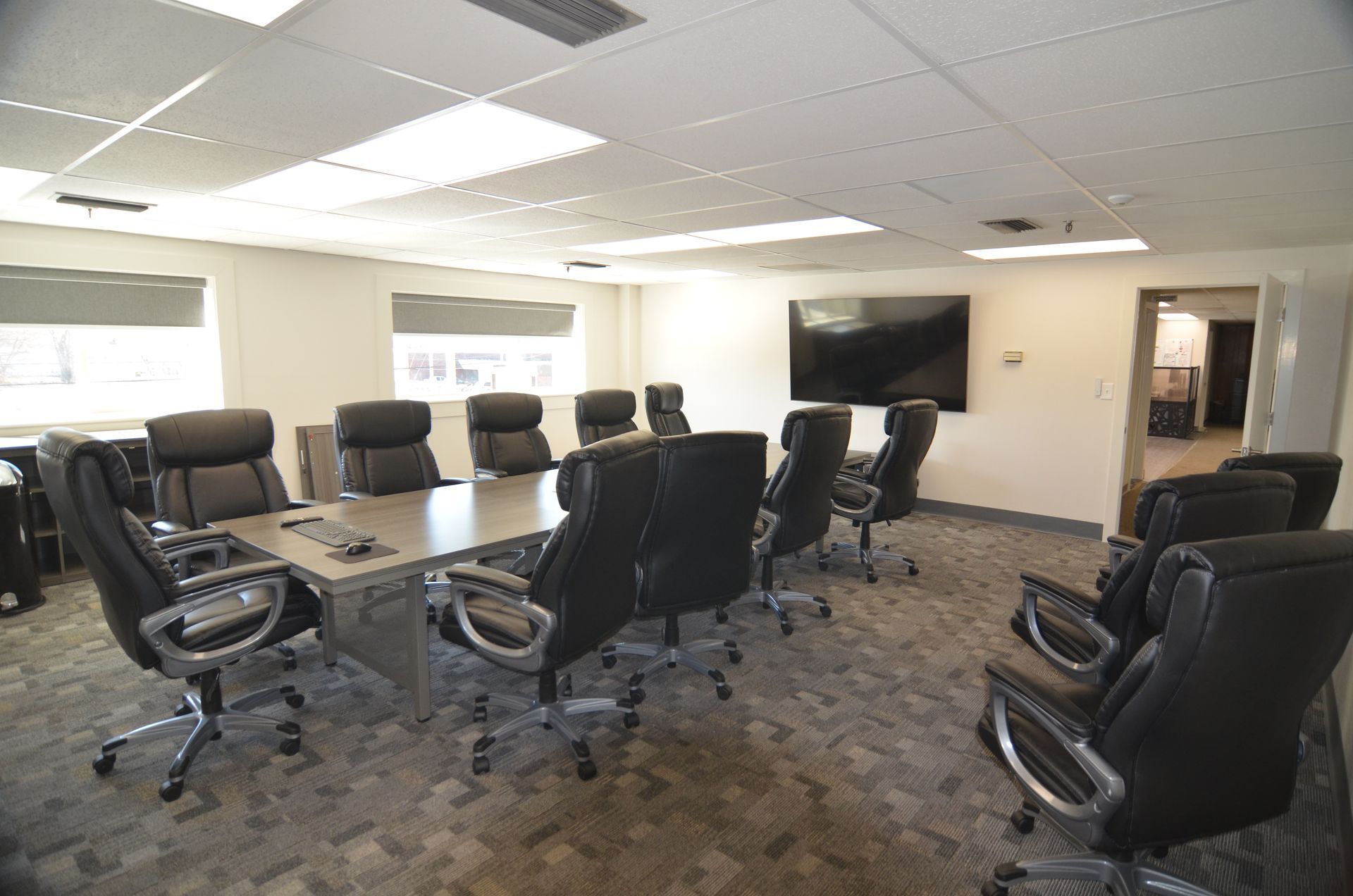 Conference room with large table, black chairs, and a mounted TV.