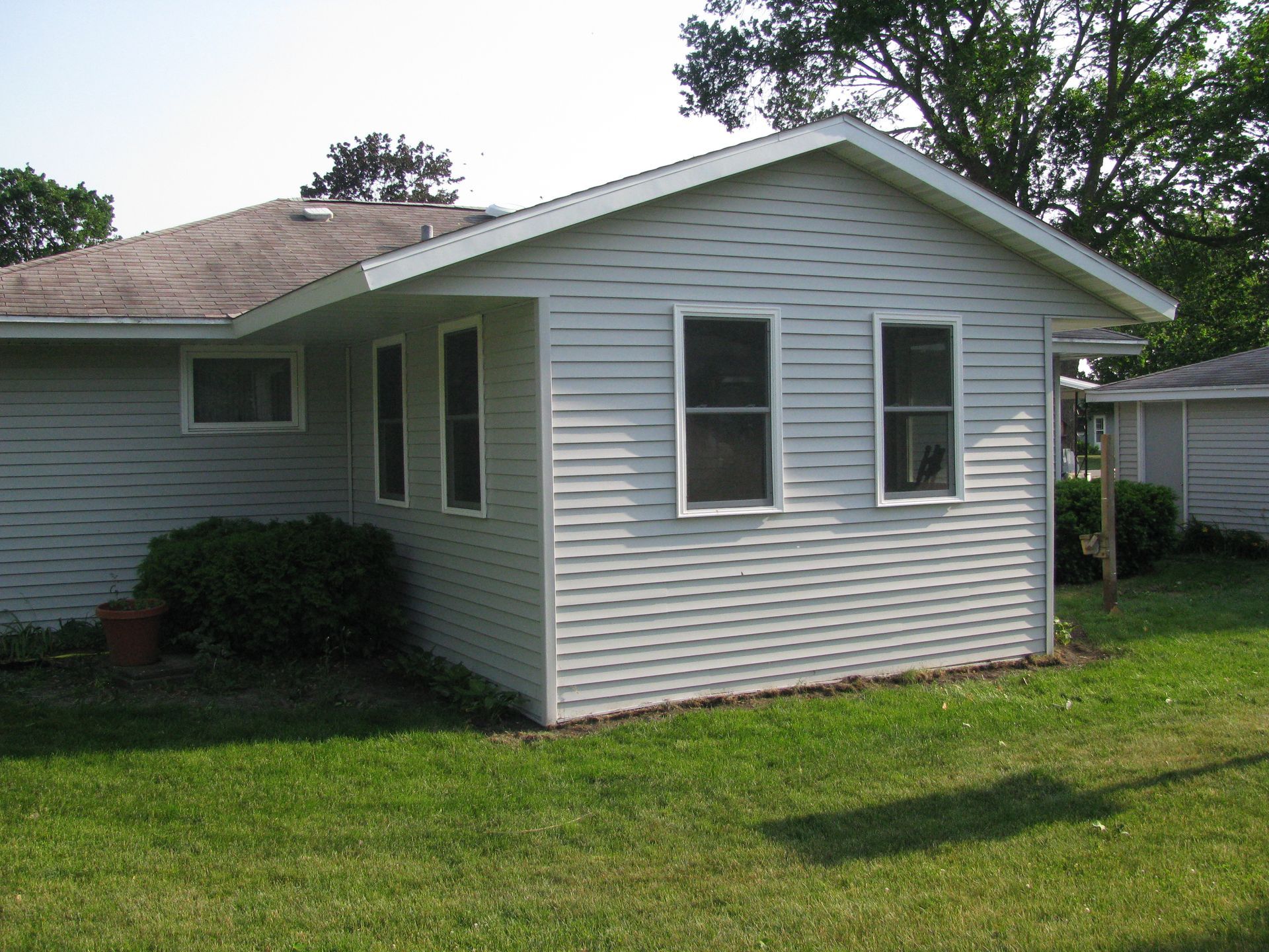 Light gray house with vinyl siding, green lawn, windows.