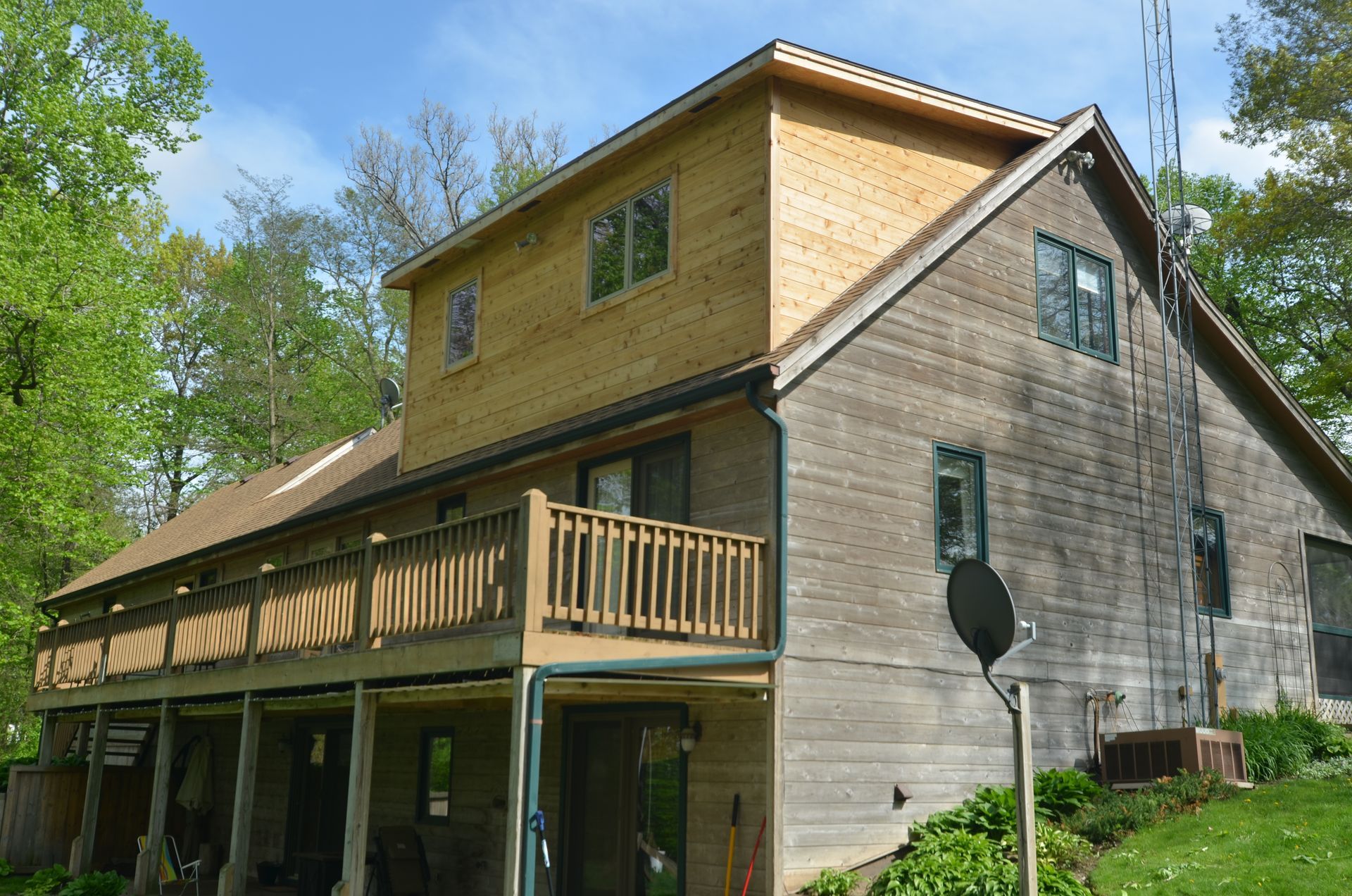 Two-story house with wood siding, a deck, and a partially new wood addition.