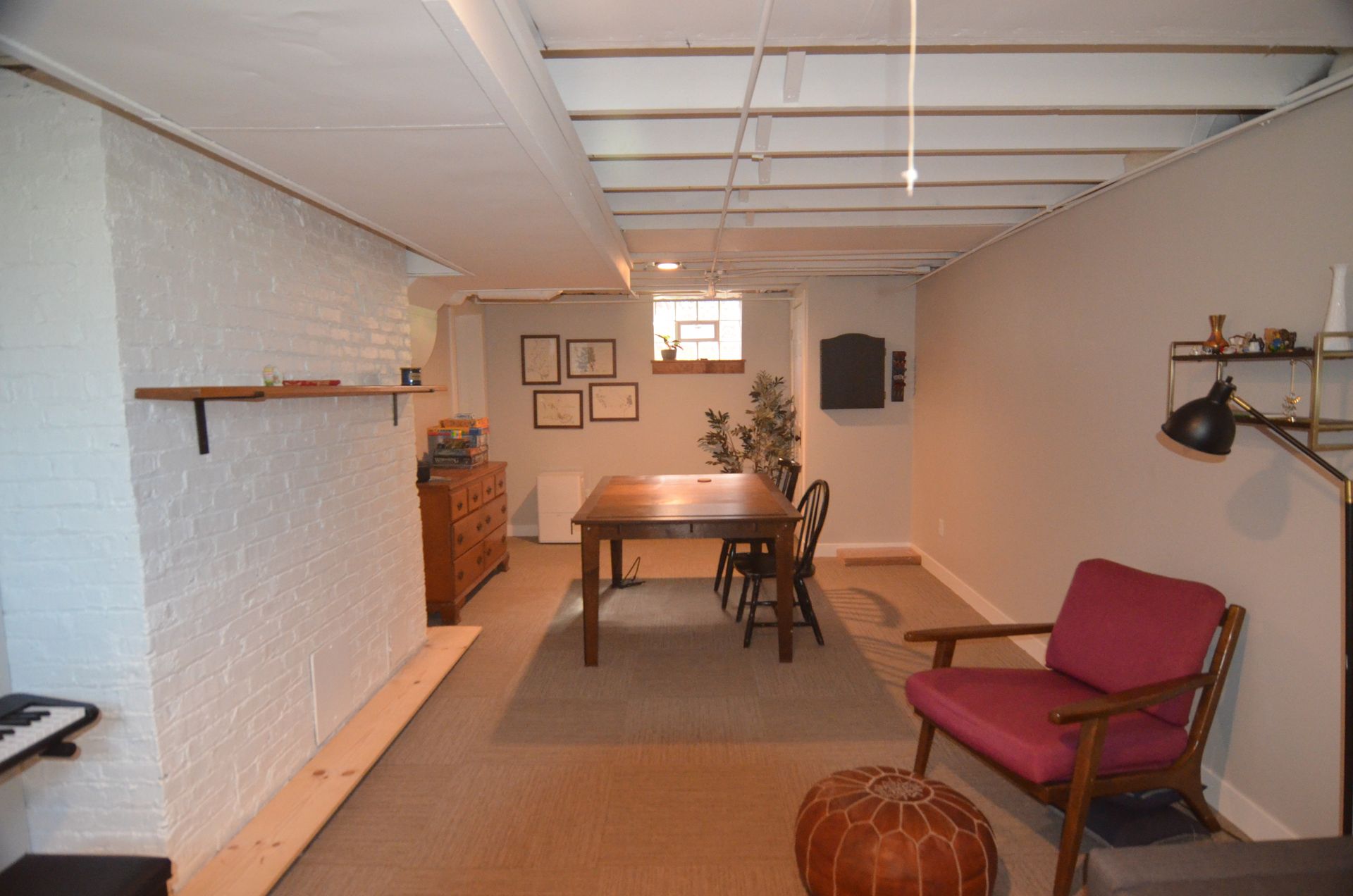 Basement room with brick wall, dining table, chair, and decorative items.