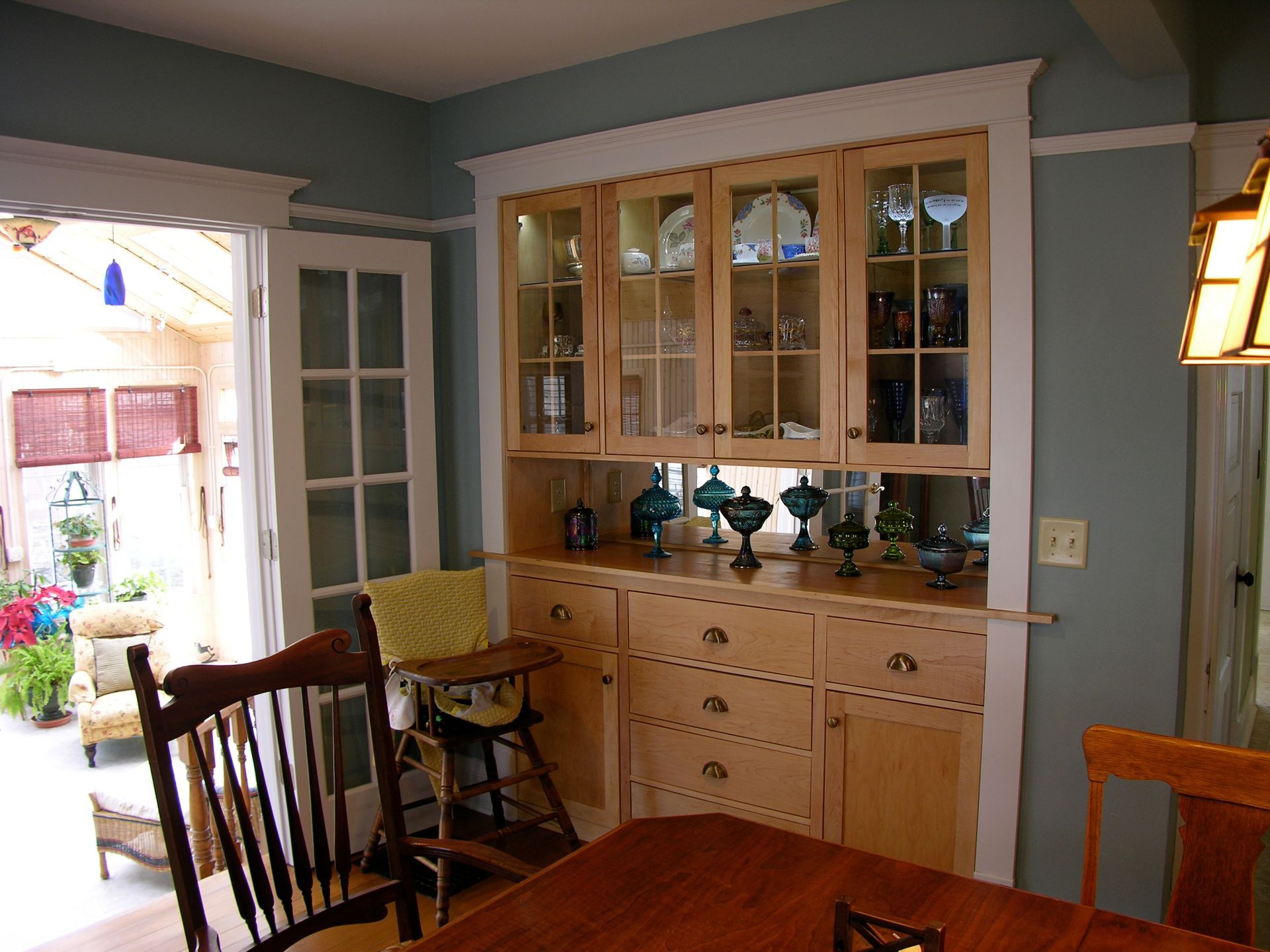 Dining room with light blue walls, built-in wooden cabinet, and French doors leading to a patio.