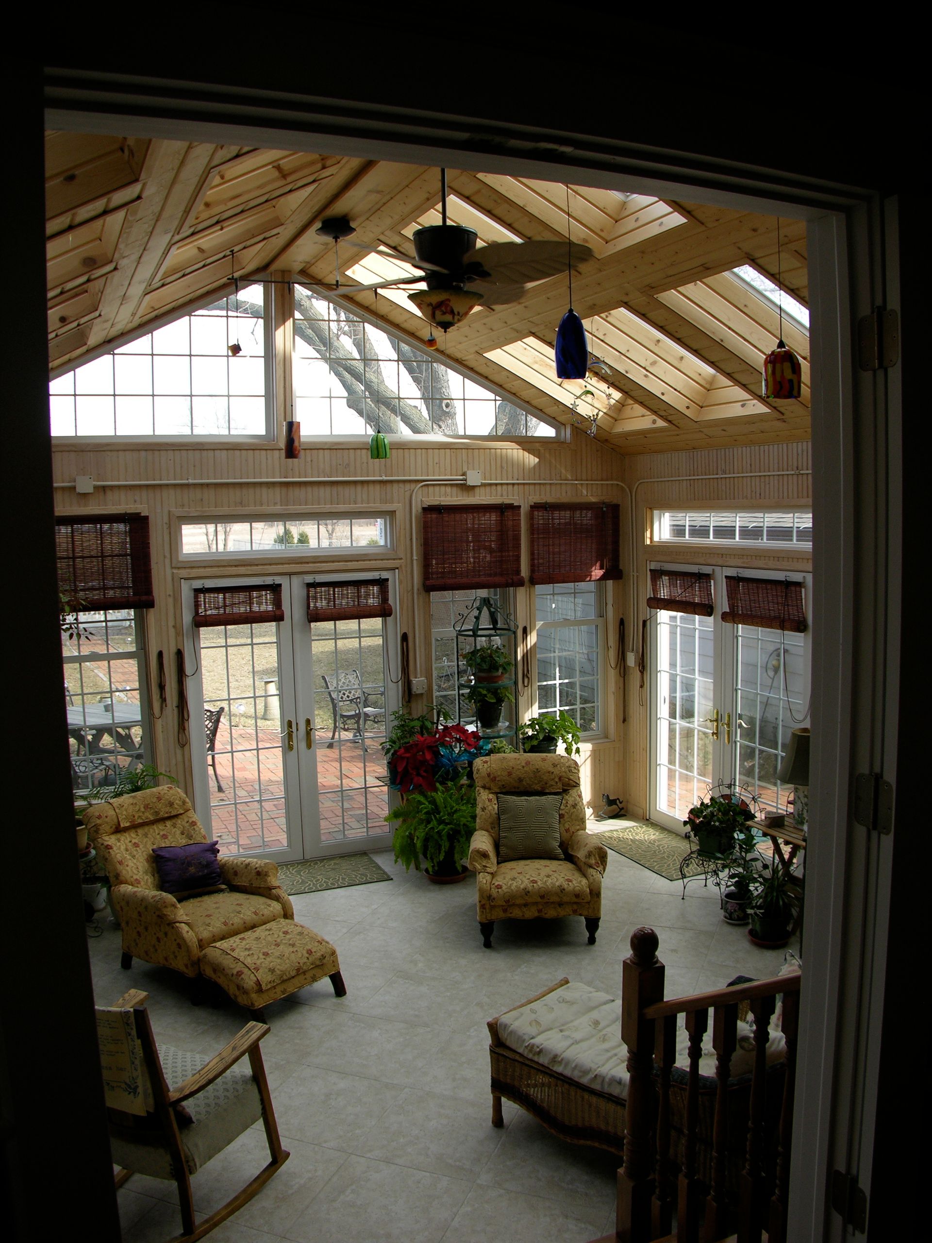 Sunroom with exposed wooden beams, windows, and lounge chairs.