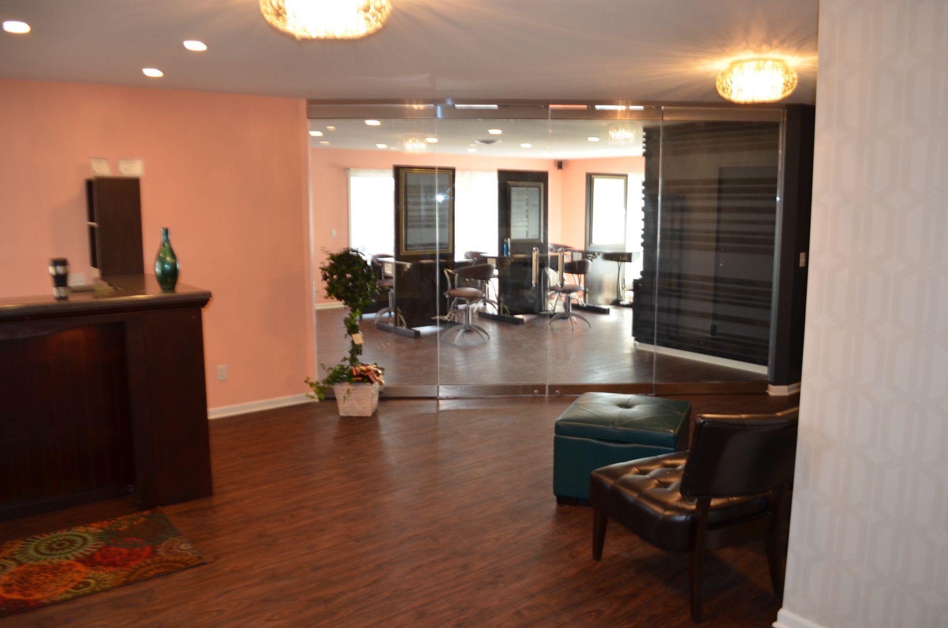 Hair salon interior with dark wood floors, pink walls, and styling stations in the background.
