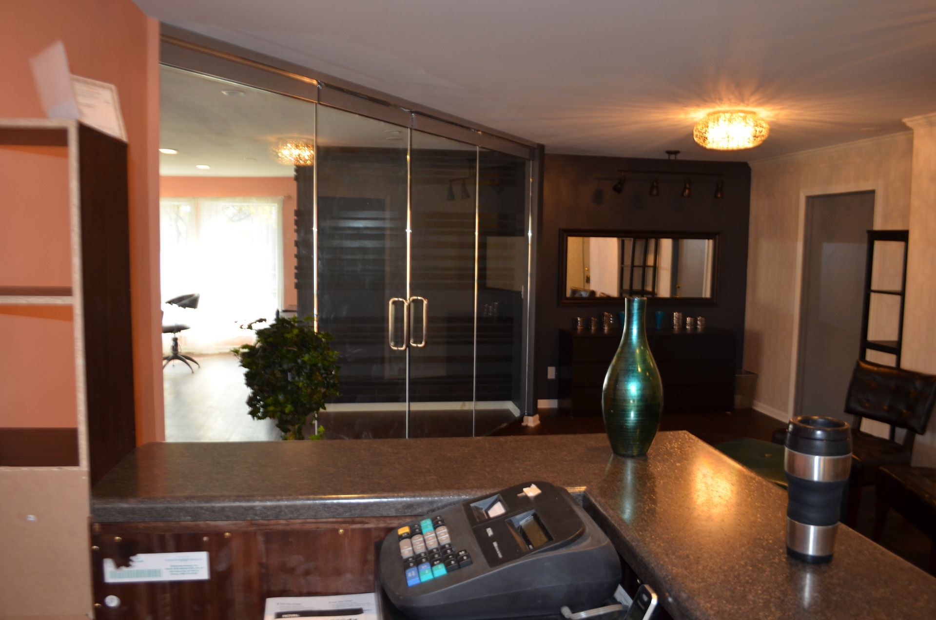 Interior salon view with reception counter, glass doors, and dark wall features.