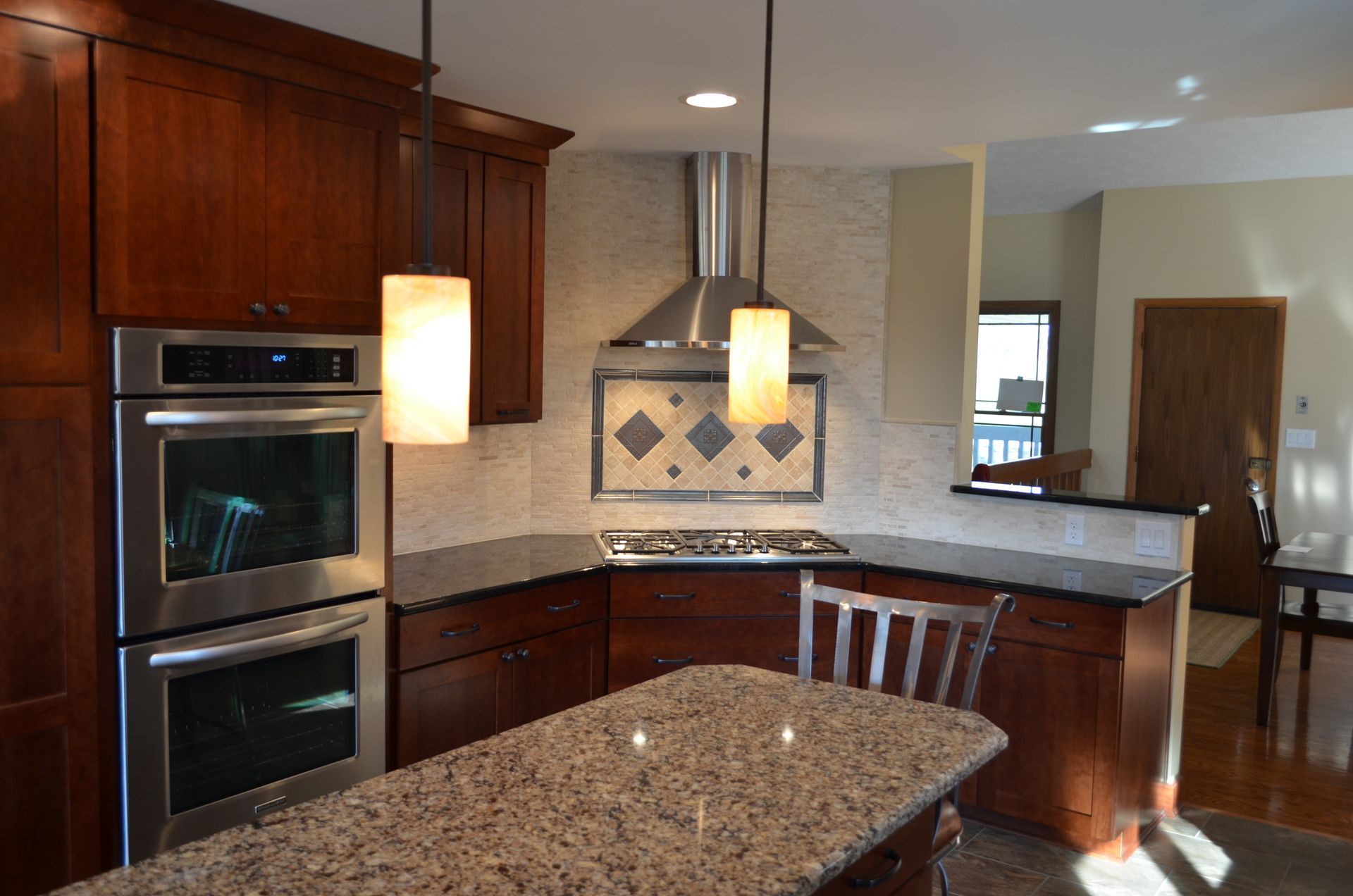 Modern kitchen with granite countertops, wooden cabinets, and stainless steel appliances.