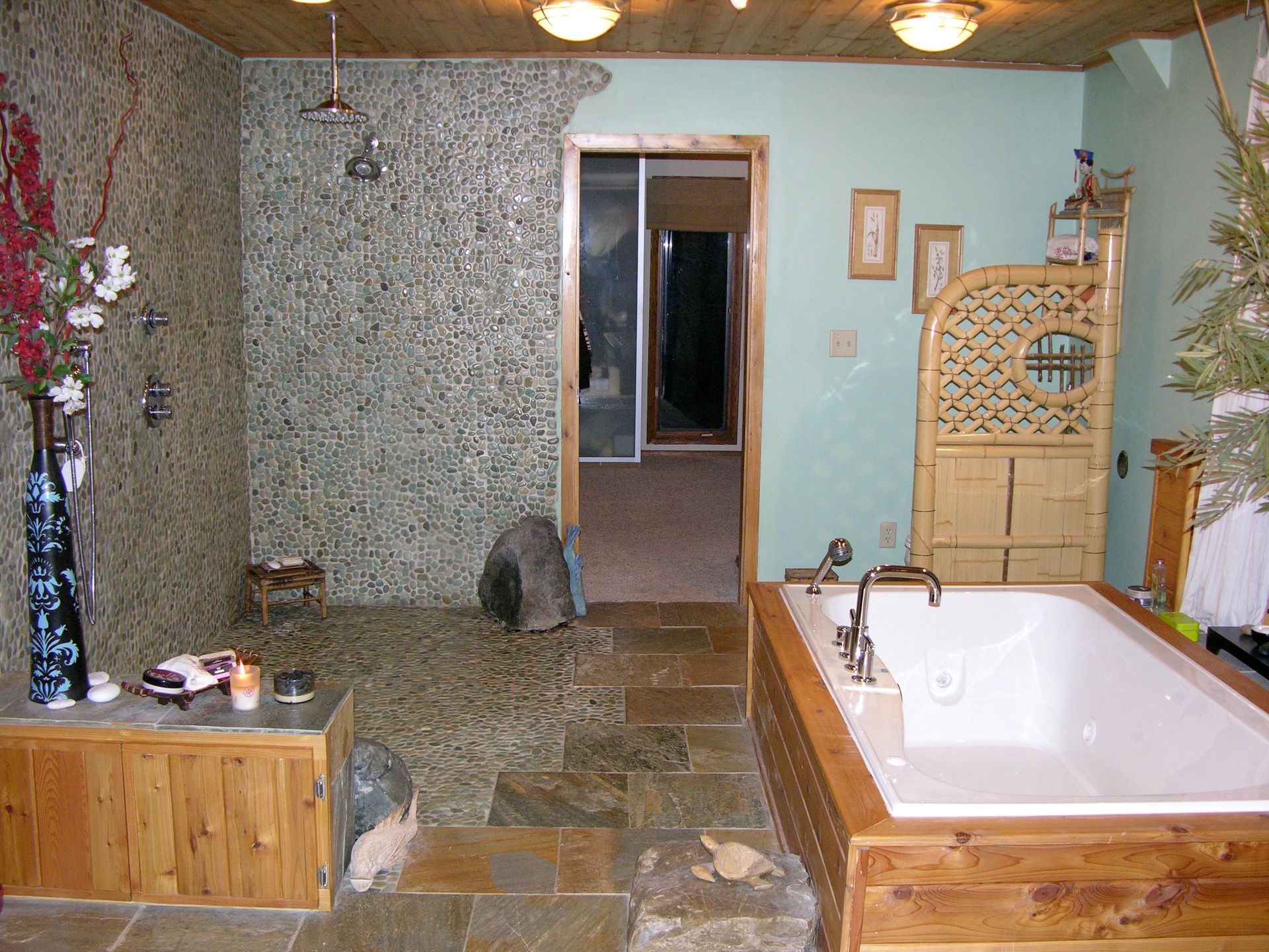 Bathroom with stone shower and tub surrounded by wood. Doorway leads to another room.