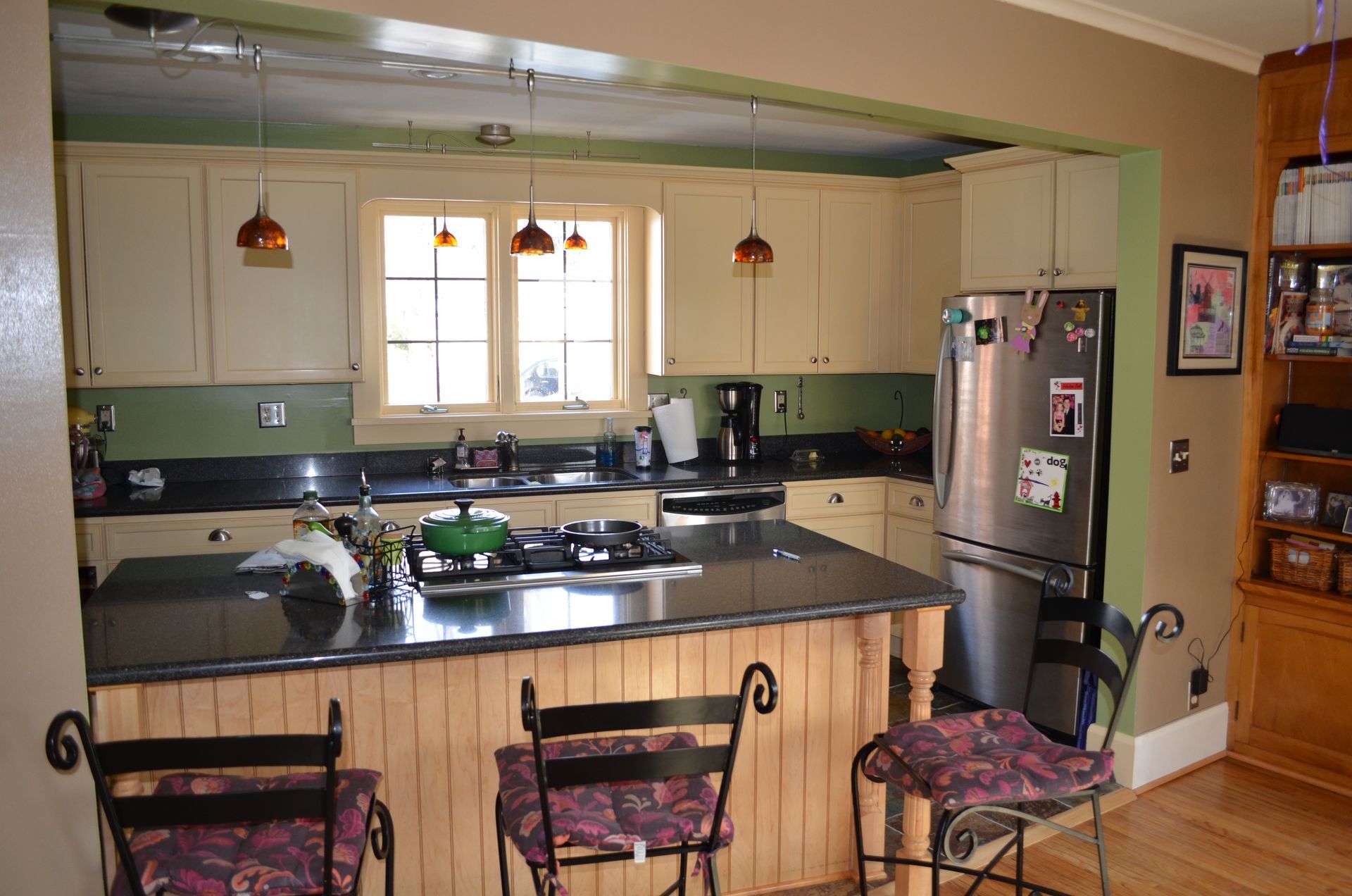 Kitchen with cream cabinets, black countertops, and a stainless steel refrigerator.