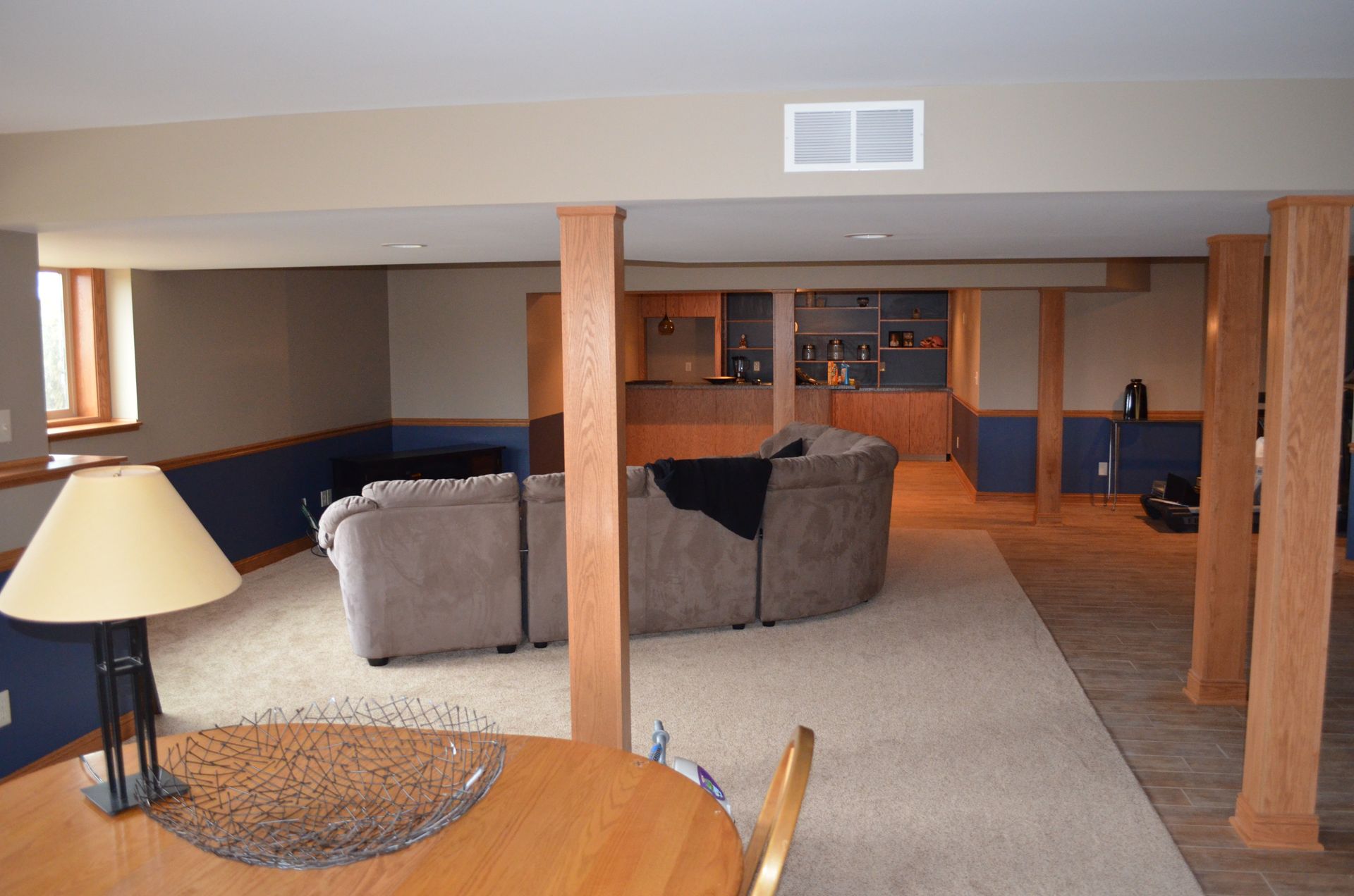 Spacious finished basement with neutral walls, columns, carpet, and a sectional sofa.