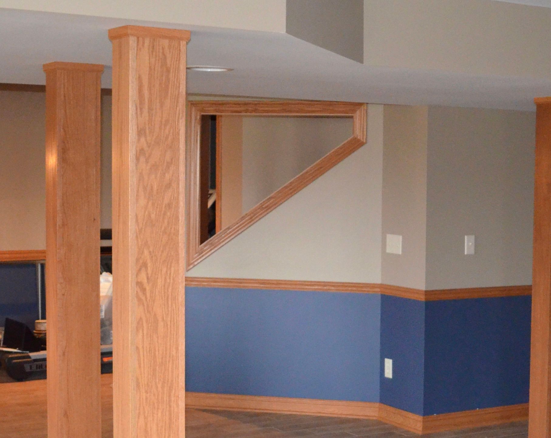 Finished basement with wooden columns, blue and tan walls, and a window.