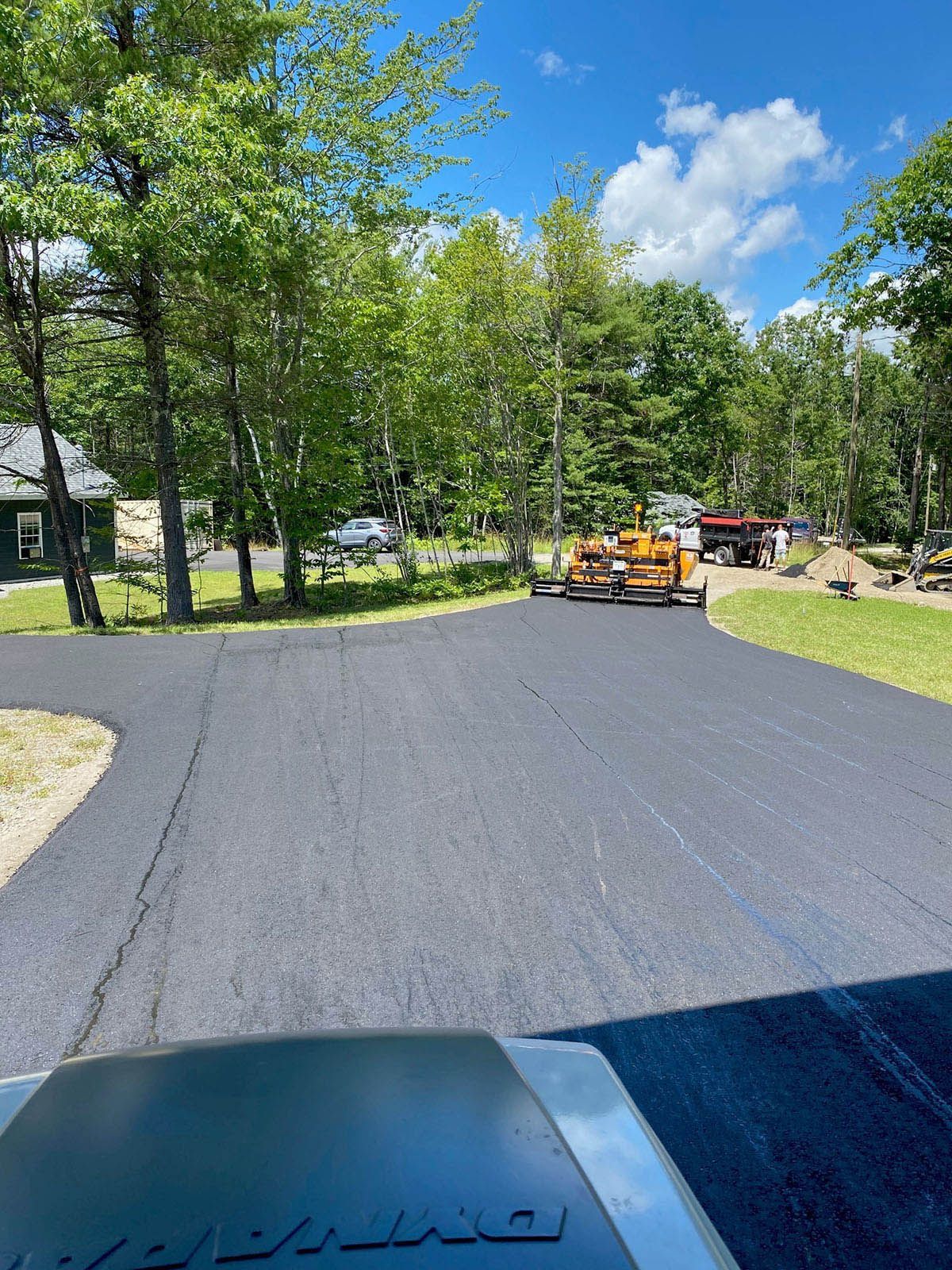 A tractor is driving down a road next to a house