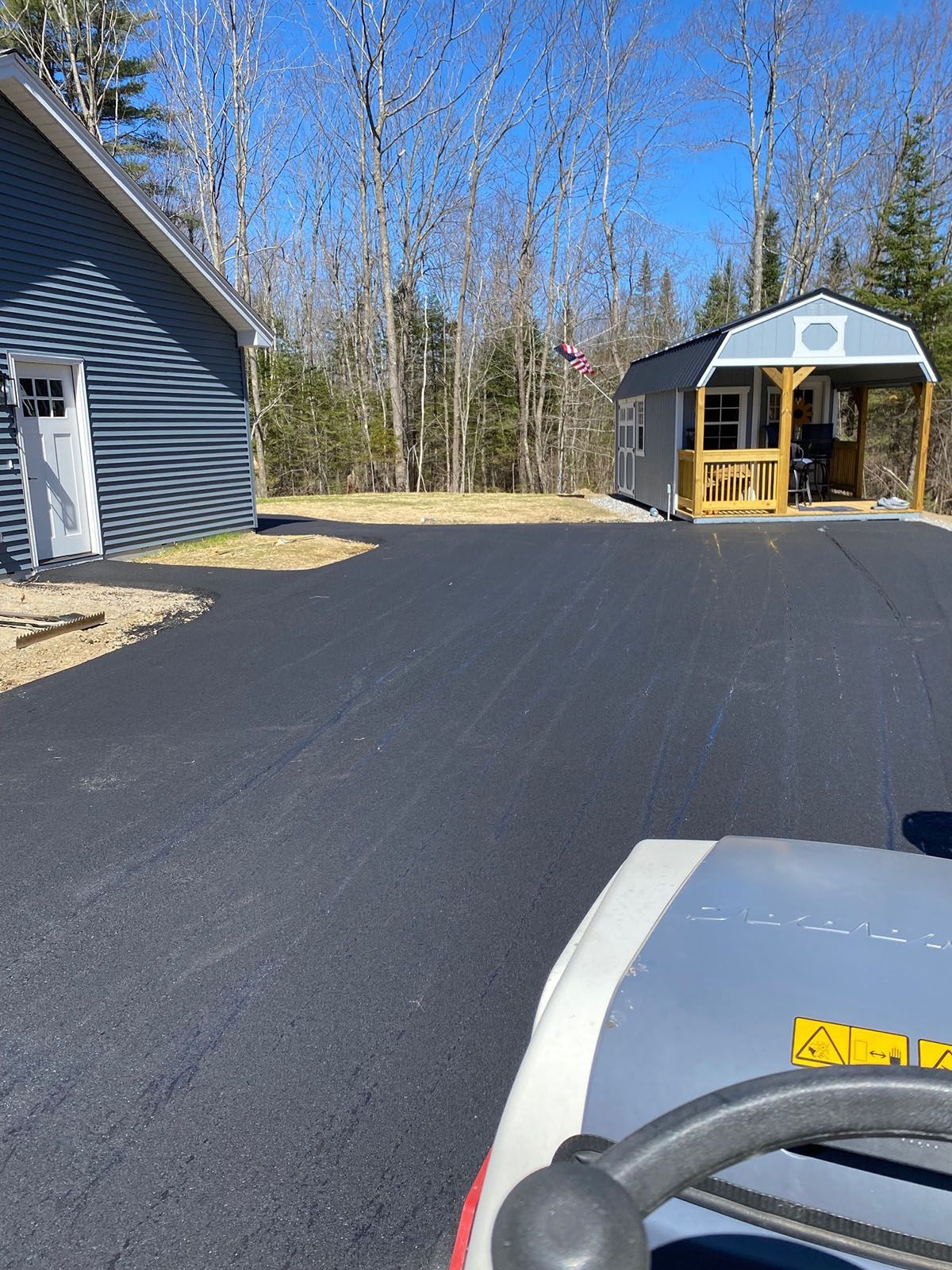 A tractor is parked in a newly paved driveway next to a house