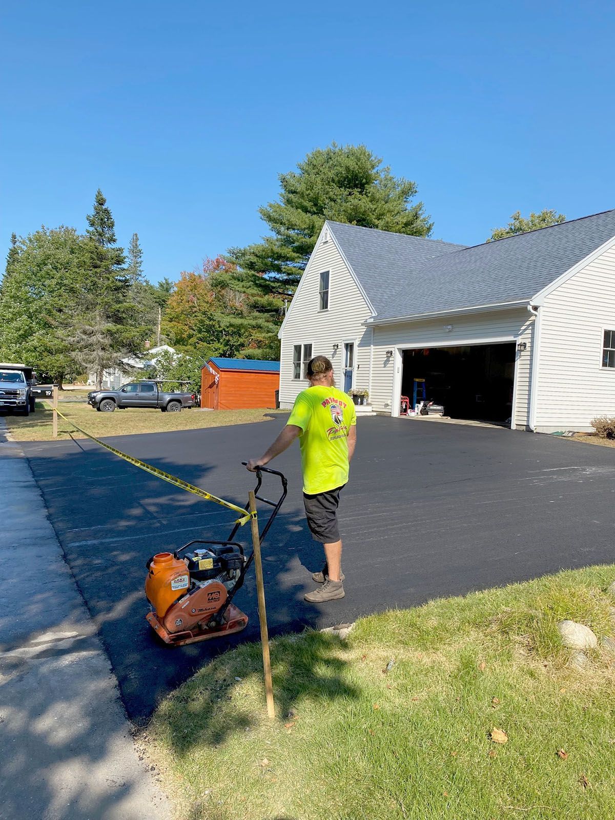 A man paving a driveway using a compactor
