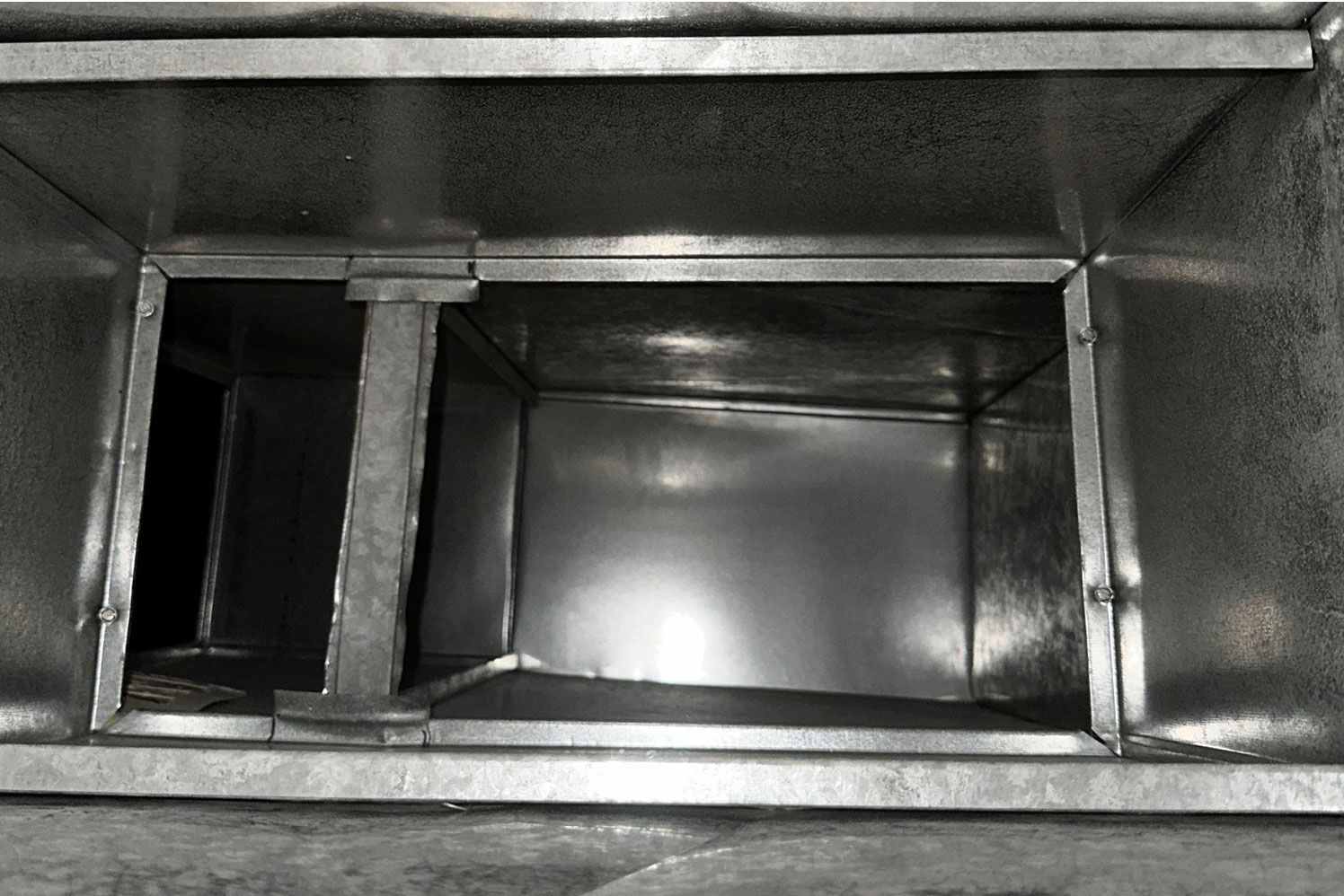 A black and white photo of a metal duct.