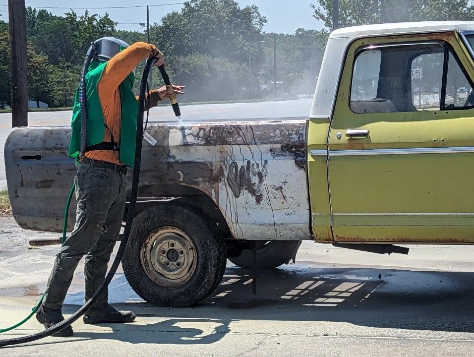 a man is sandblasting a truck in a parking lot