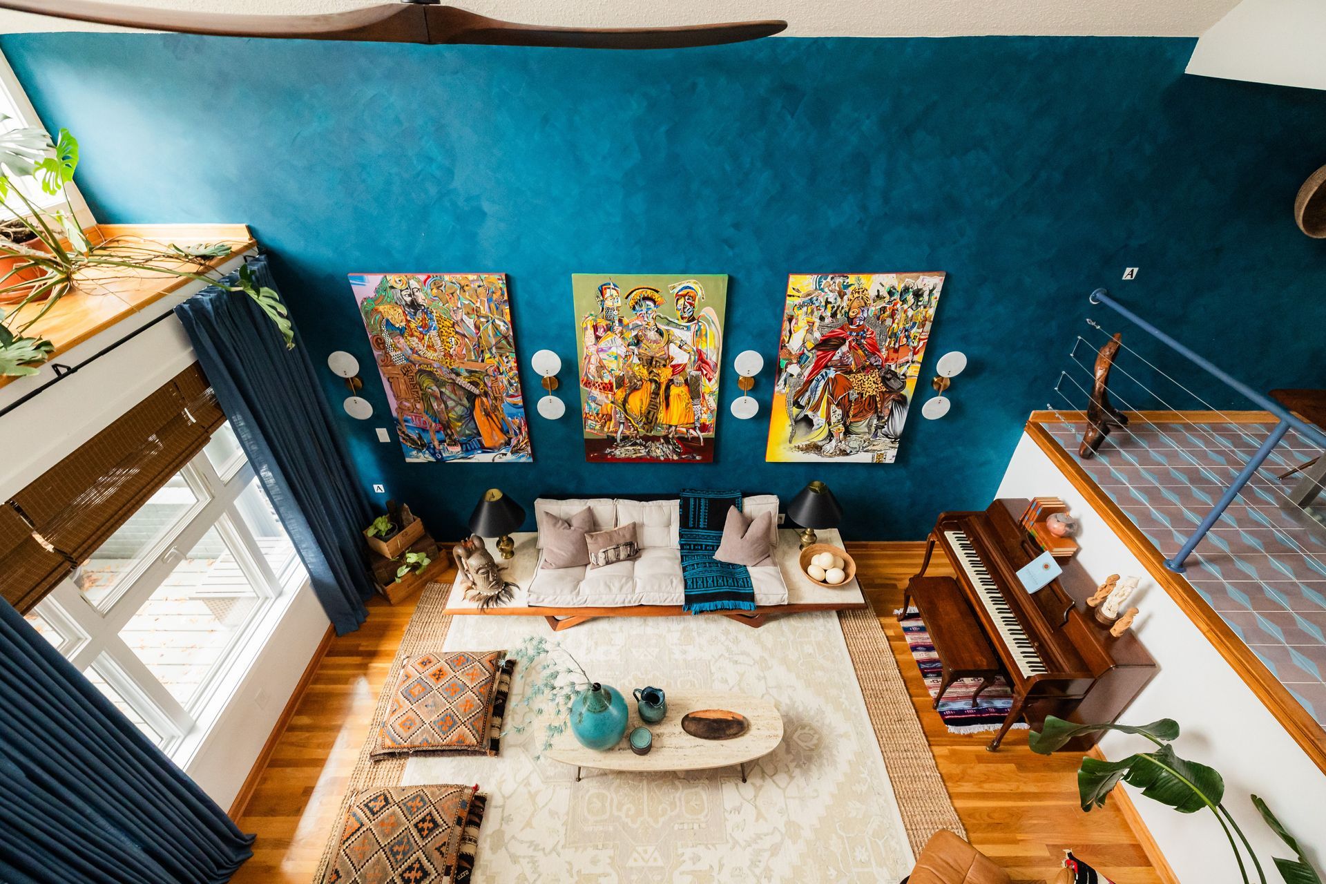 An overhead view of a brightly colored living room with a blue wall, art, piano, and seating area.
