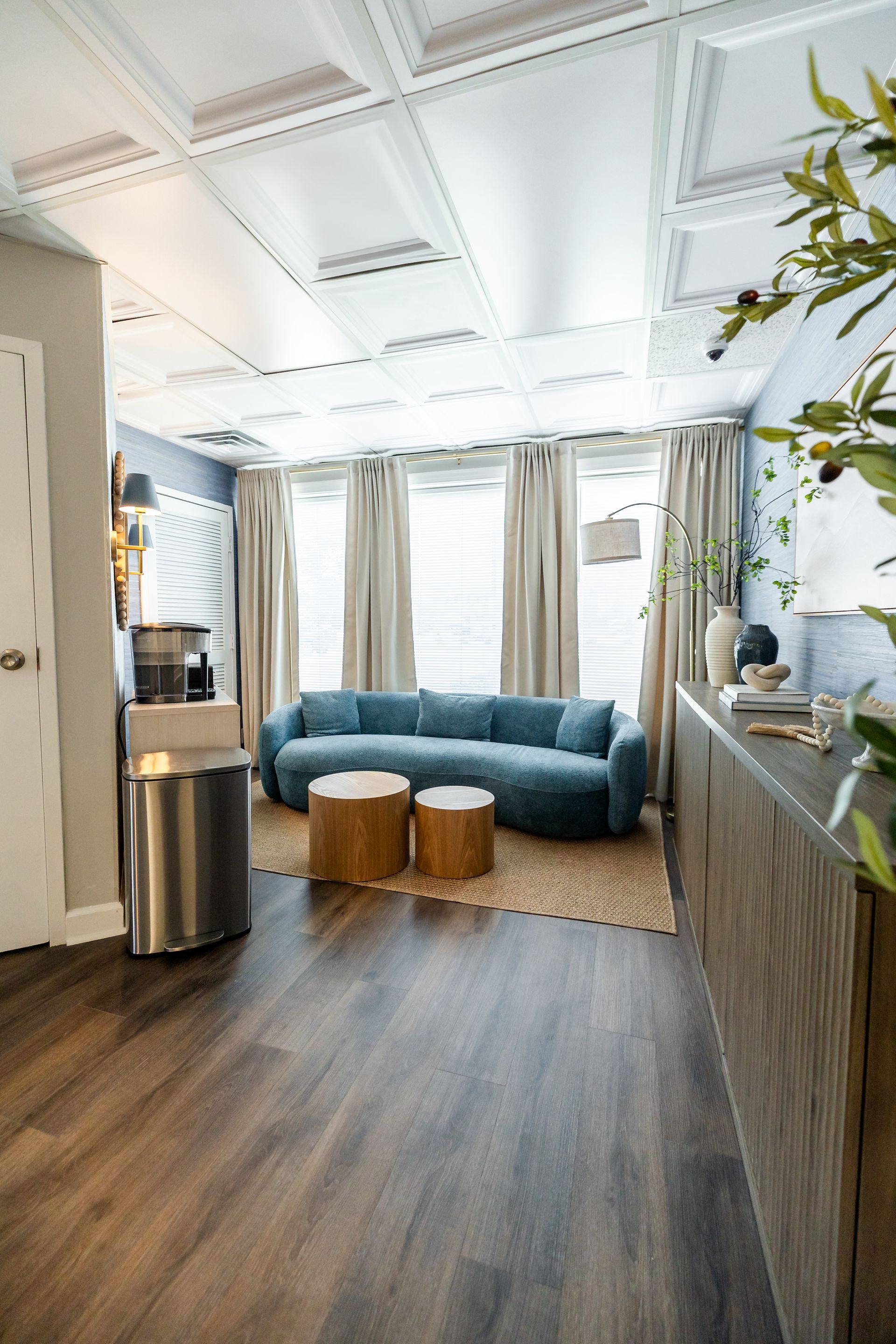 Living room with a blue couch, two wooden tables, and a decorative ceiling.