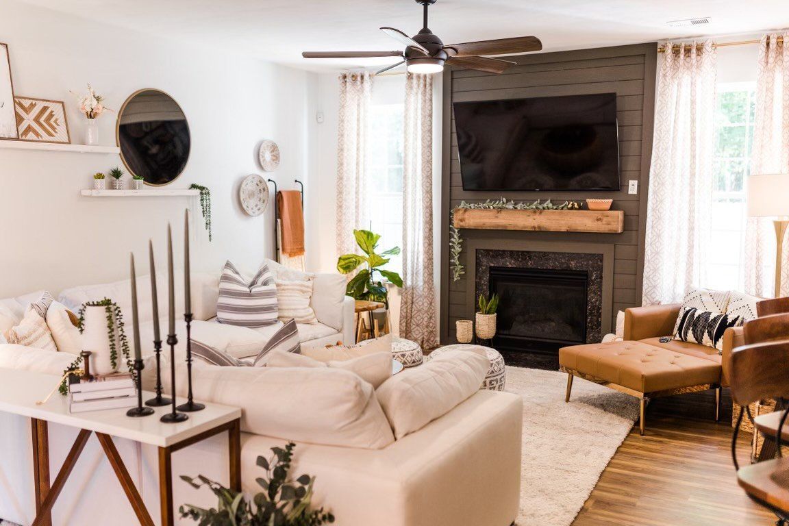 A living room with a couch , chairs , fireplace and television.