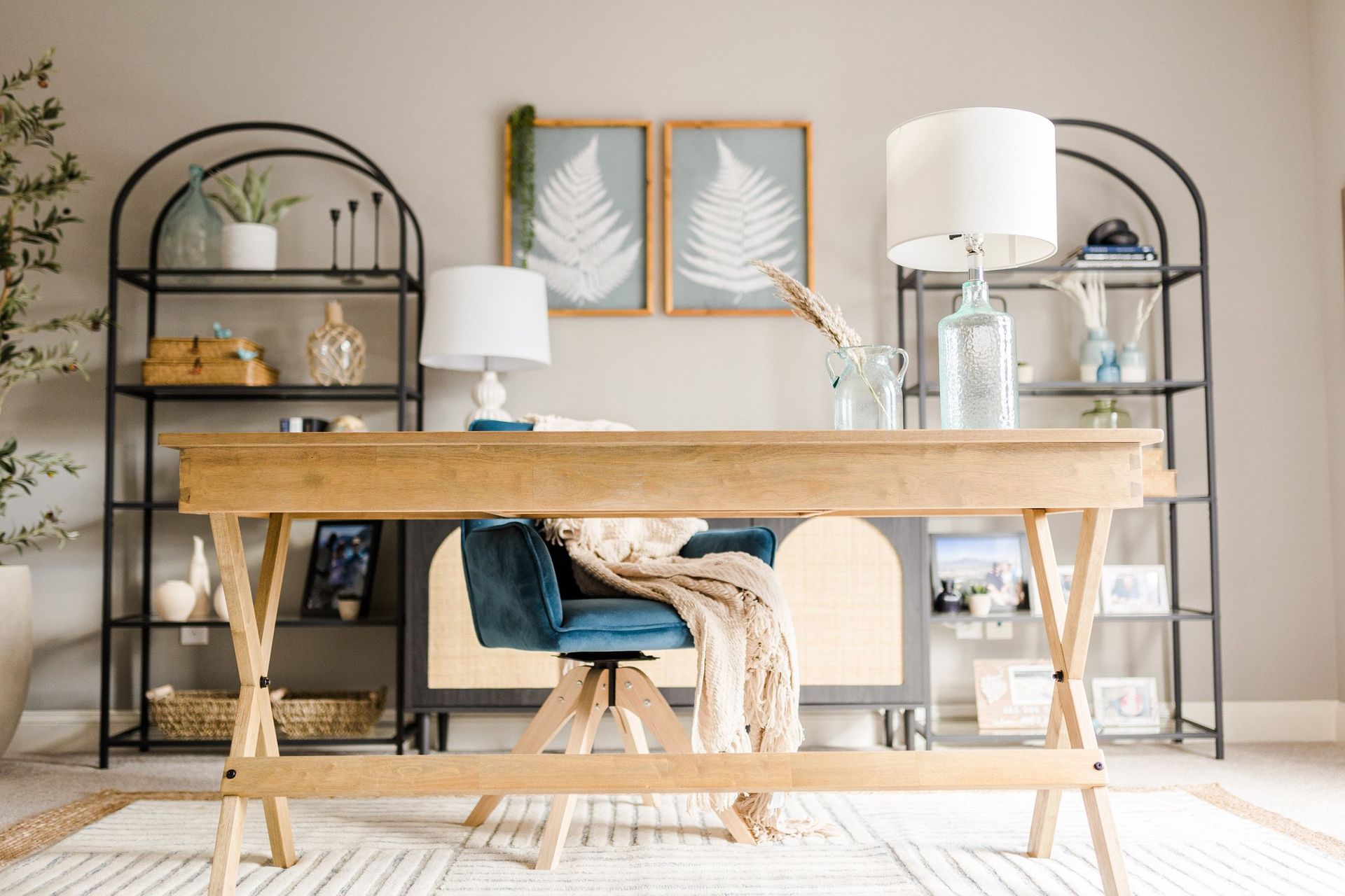A home office with a wooden desk , chair , lamps and shelves.