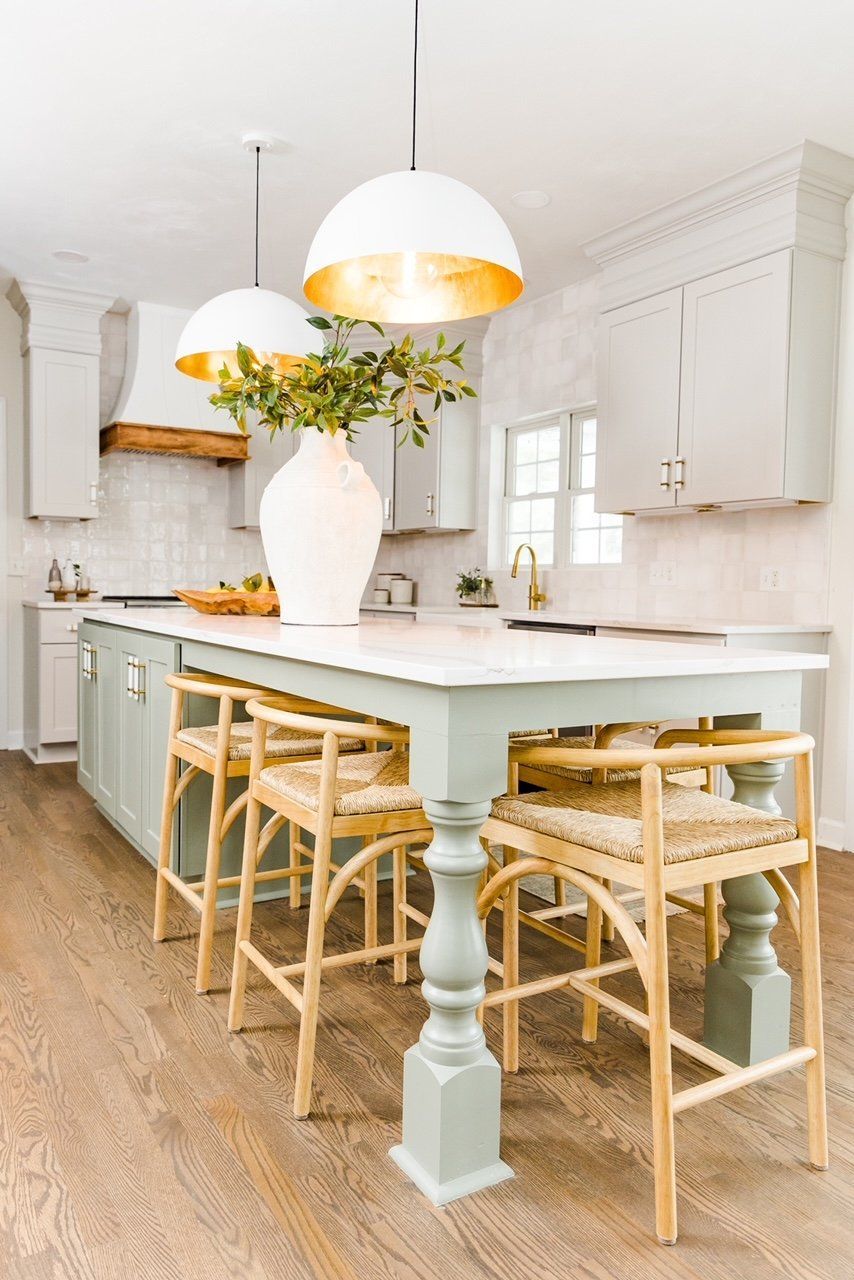 A kitchen with a large island , stools , and a table.