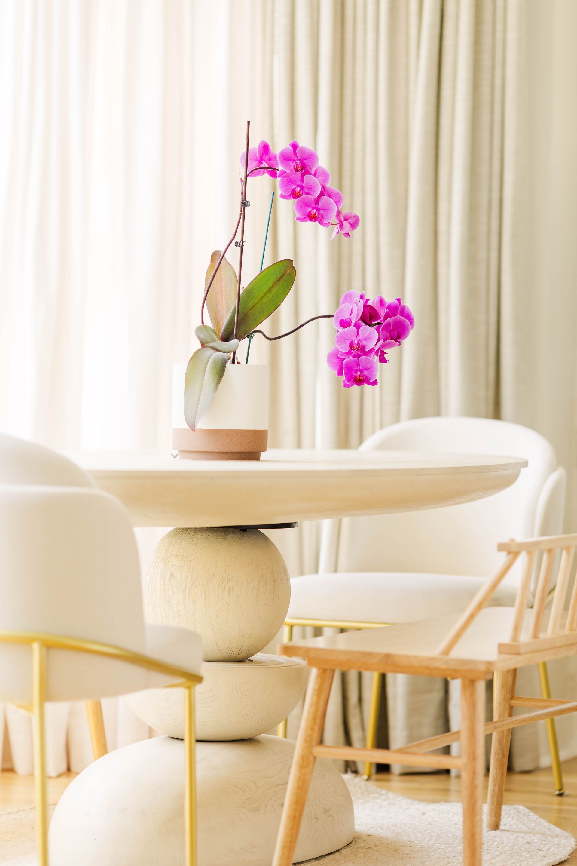 A dining room table with a vase of flowers on it.
