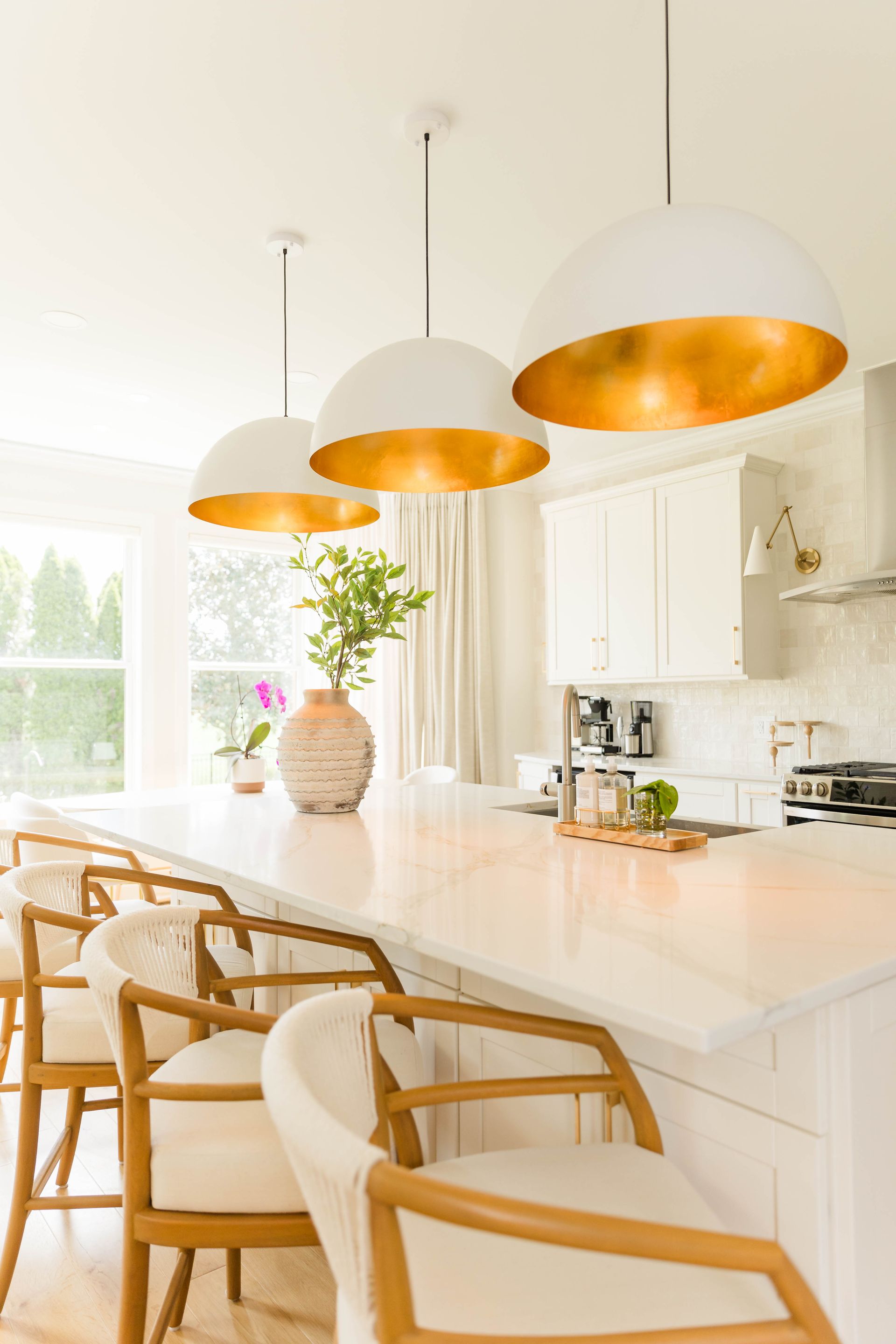 A kitchen with white cabinets and gold pendant lights hanging from the ceiling.