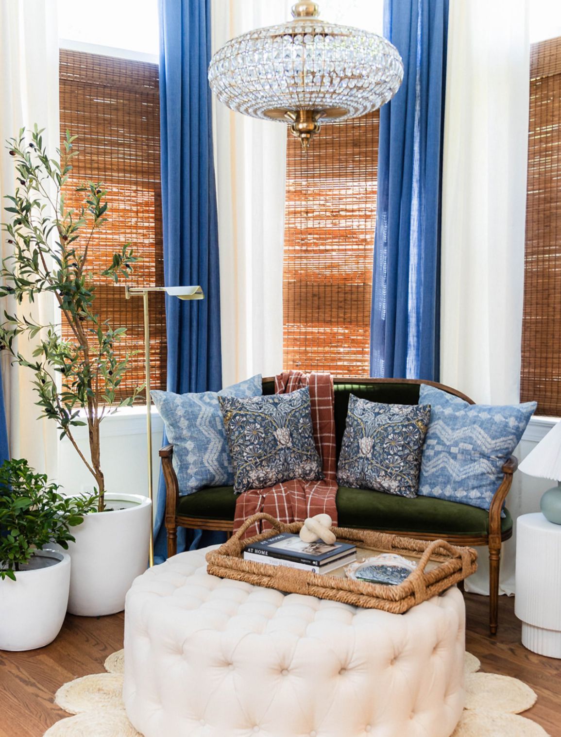 A living room with a couch, ottoman, coffee table, and plants.