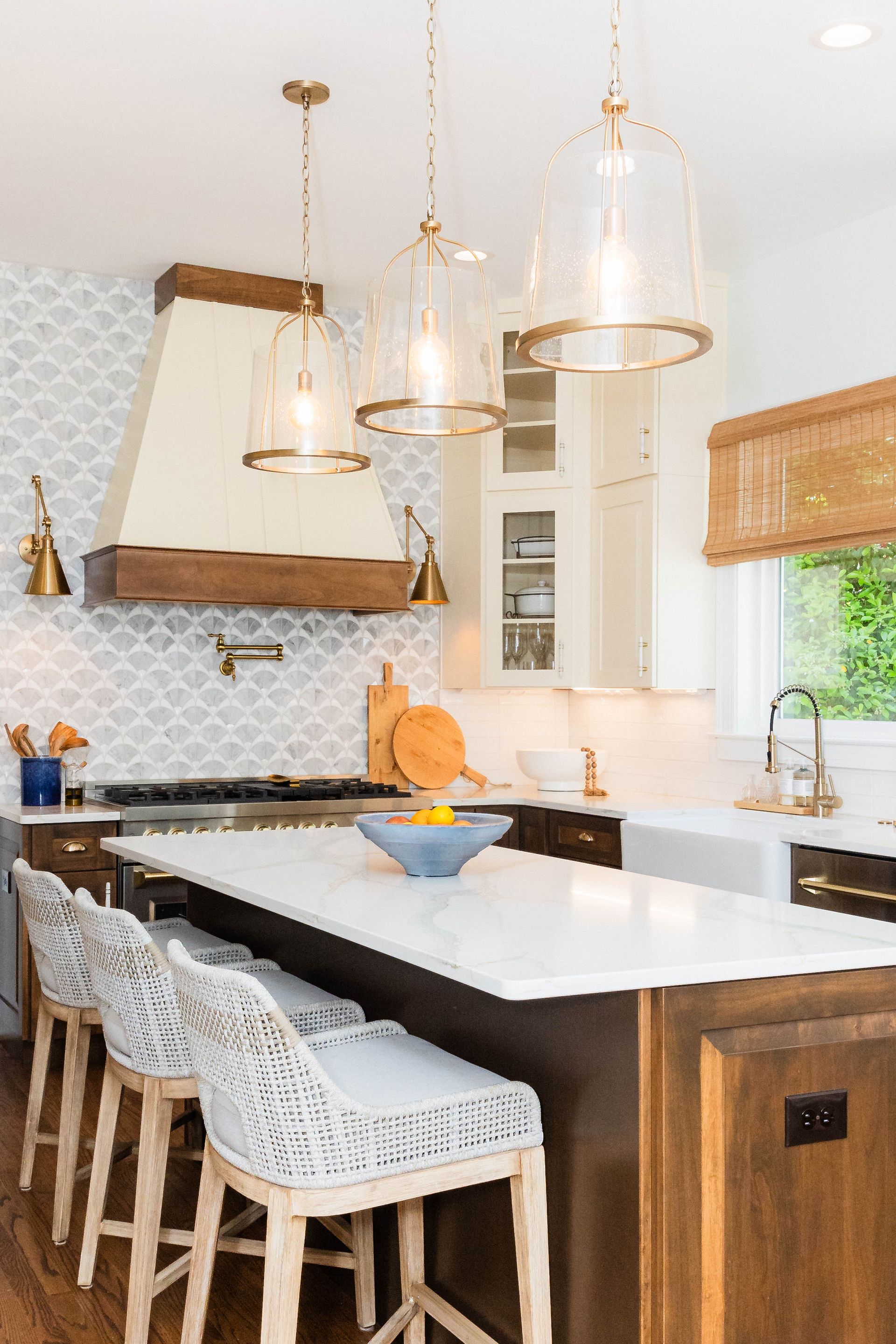 A kitchen with a large island, stools, and a stove.