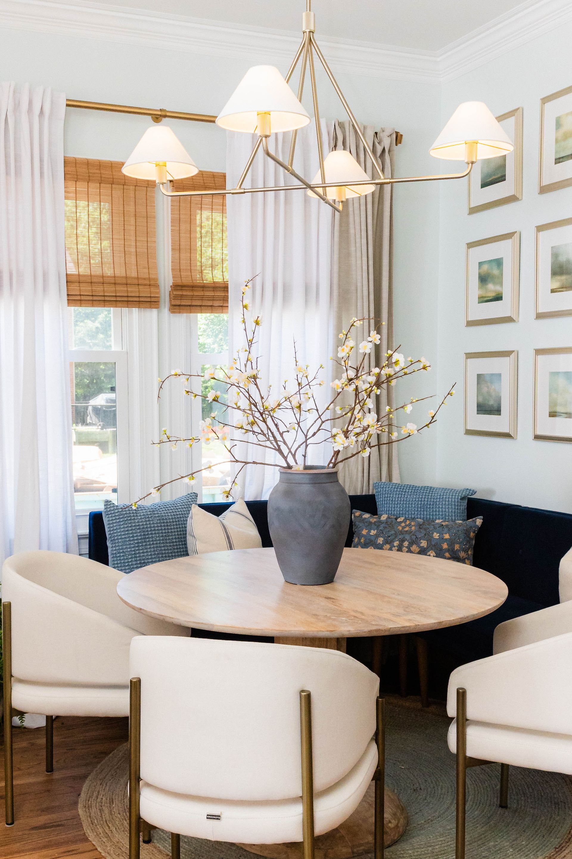 A dining room with a table and chairs and a vase of flowers on the table.