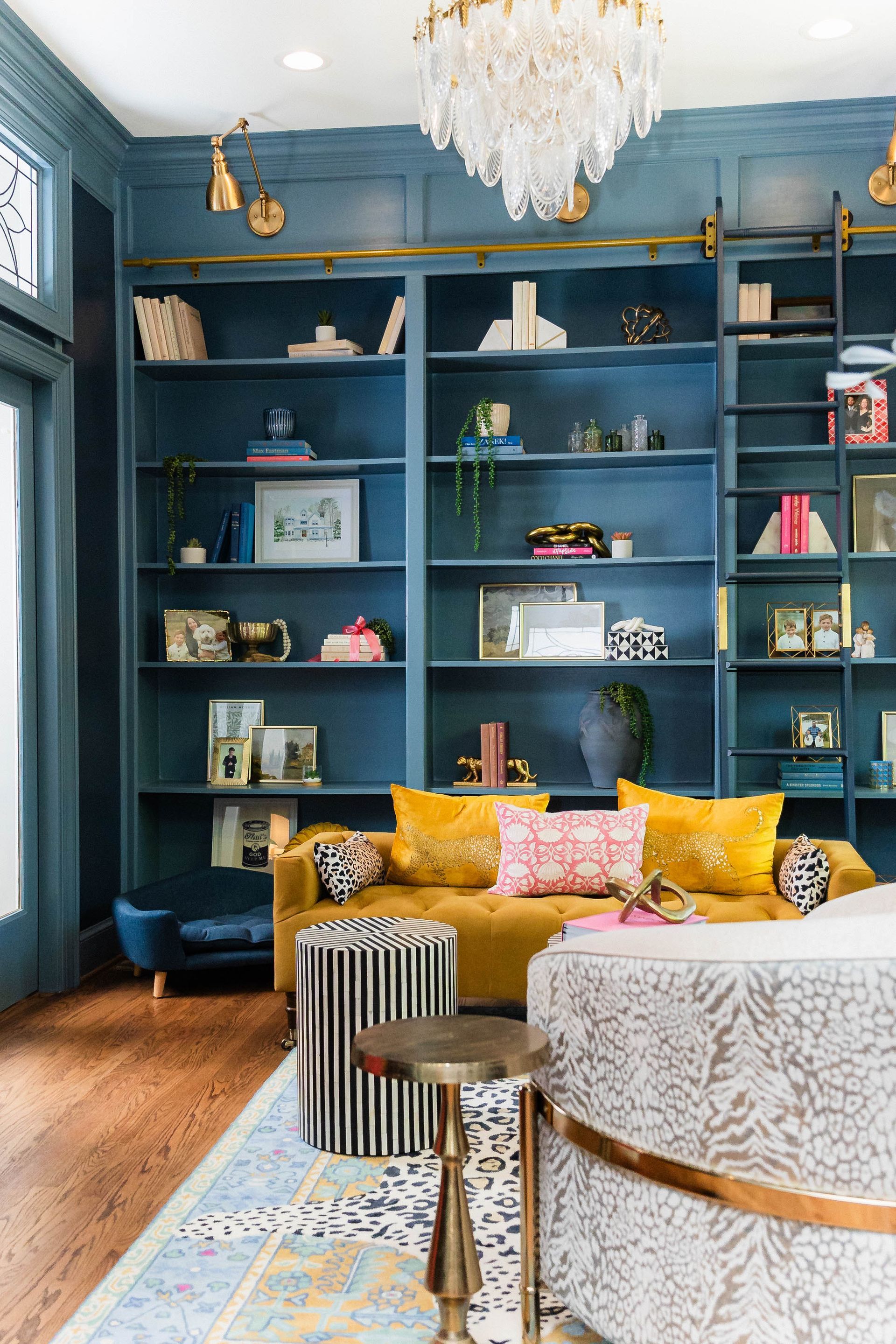 A living room with a couch, shelves, and a chandelier.