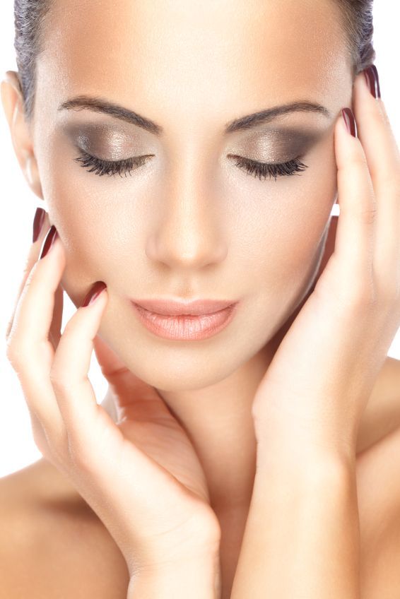 A close up of a woman 's face with her eyes closed and her hands on her face.