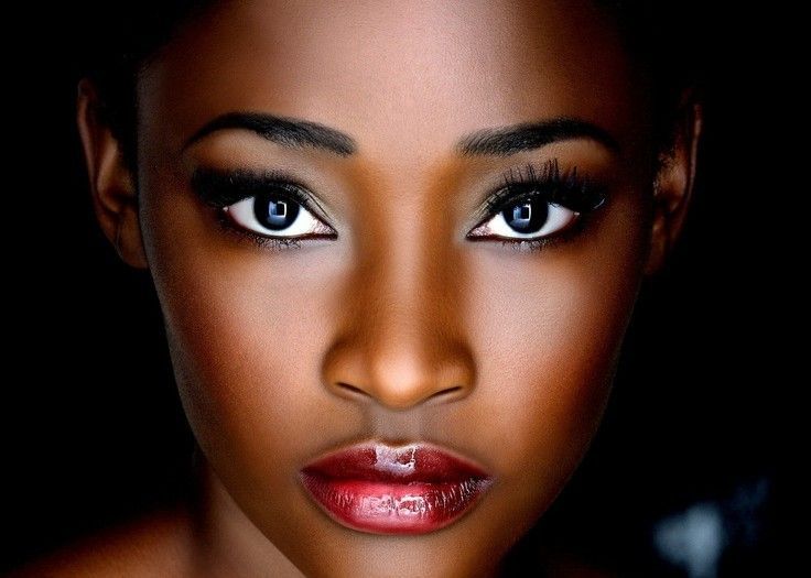 A close up of a woman 's face with blue eyes and red lips.