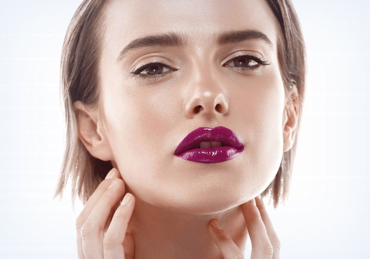 A close up of a woman 's face with purple lipstick.