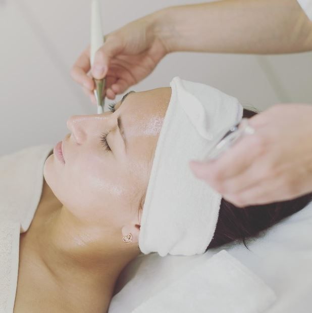 A woman is getting a facial treatment at a spa
