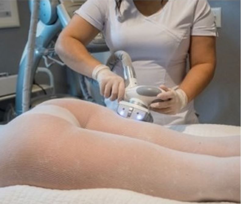 A woman is laying on a bed getting a treatment on her legs.