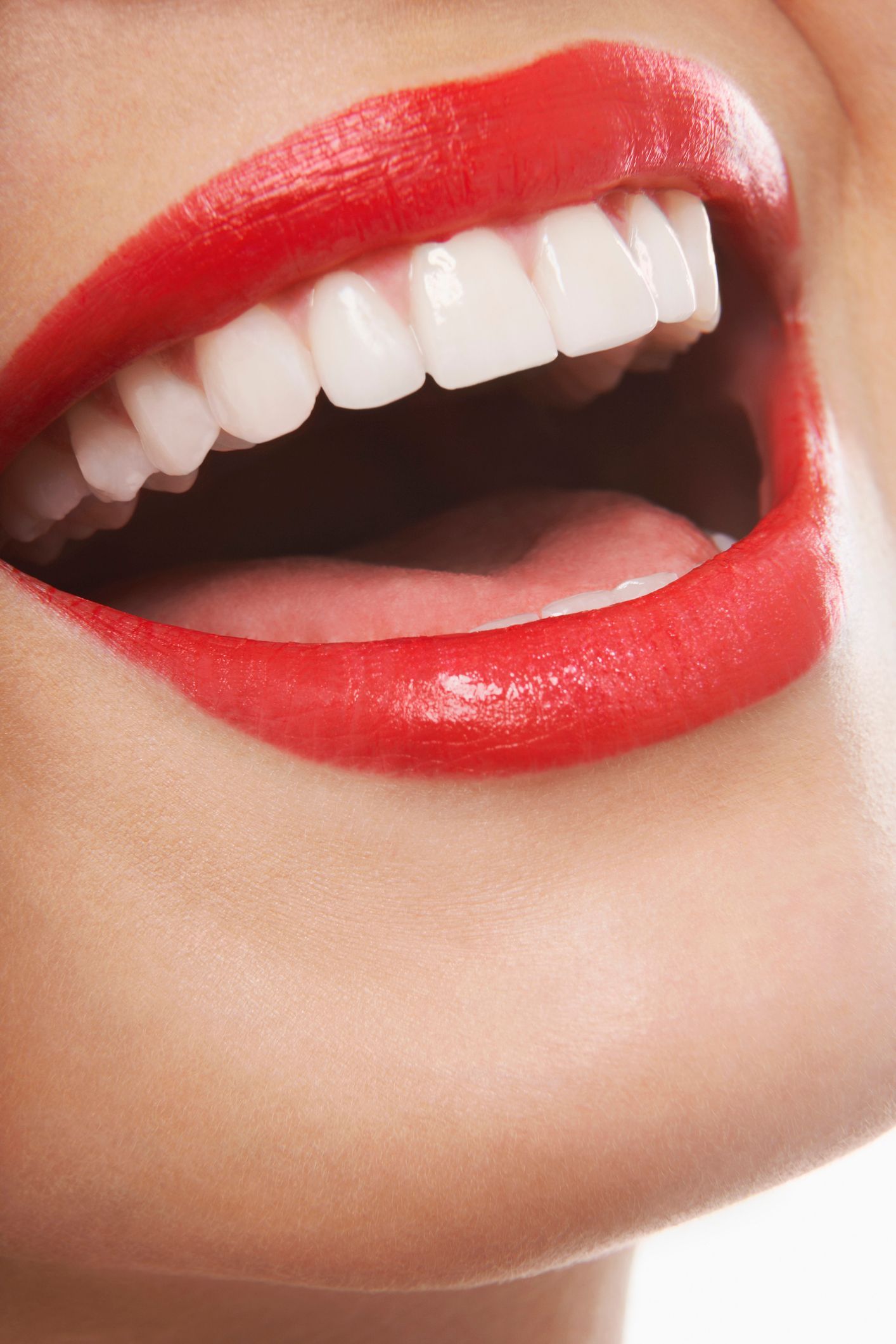Close-up of a smiling mouth with glossy red lipstick and white teeth