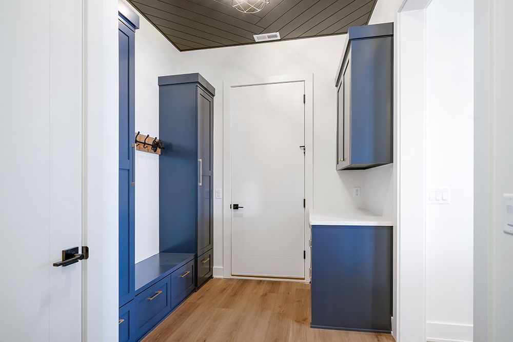 Mudroom with navy blue cabinetry and white door.