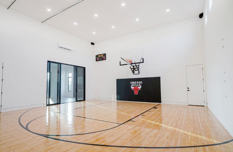 Empty indoor basketball court with Chicago Bulls logo on wall, hardwood floor, white walls.