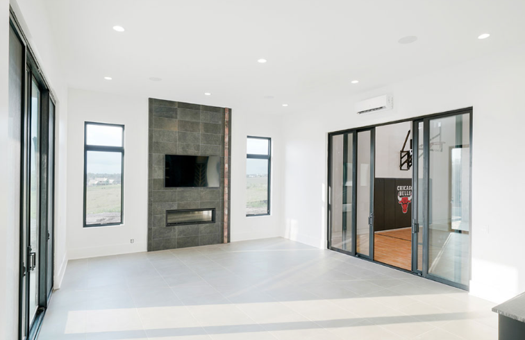 Bright, modern room with fireplace, TV, and sliding glass doors to a basketball court.