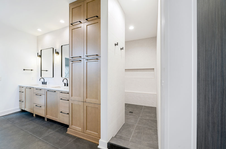 Modern bathroom with light cabinetry, double vanity, and a walk-in shower.