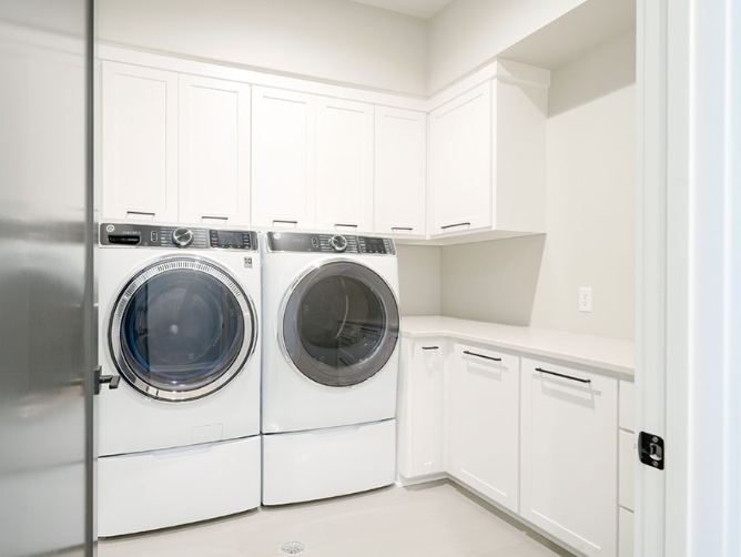 White laundry room with washer, dryer, cabinets, and countertop.